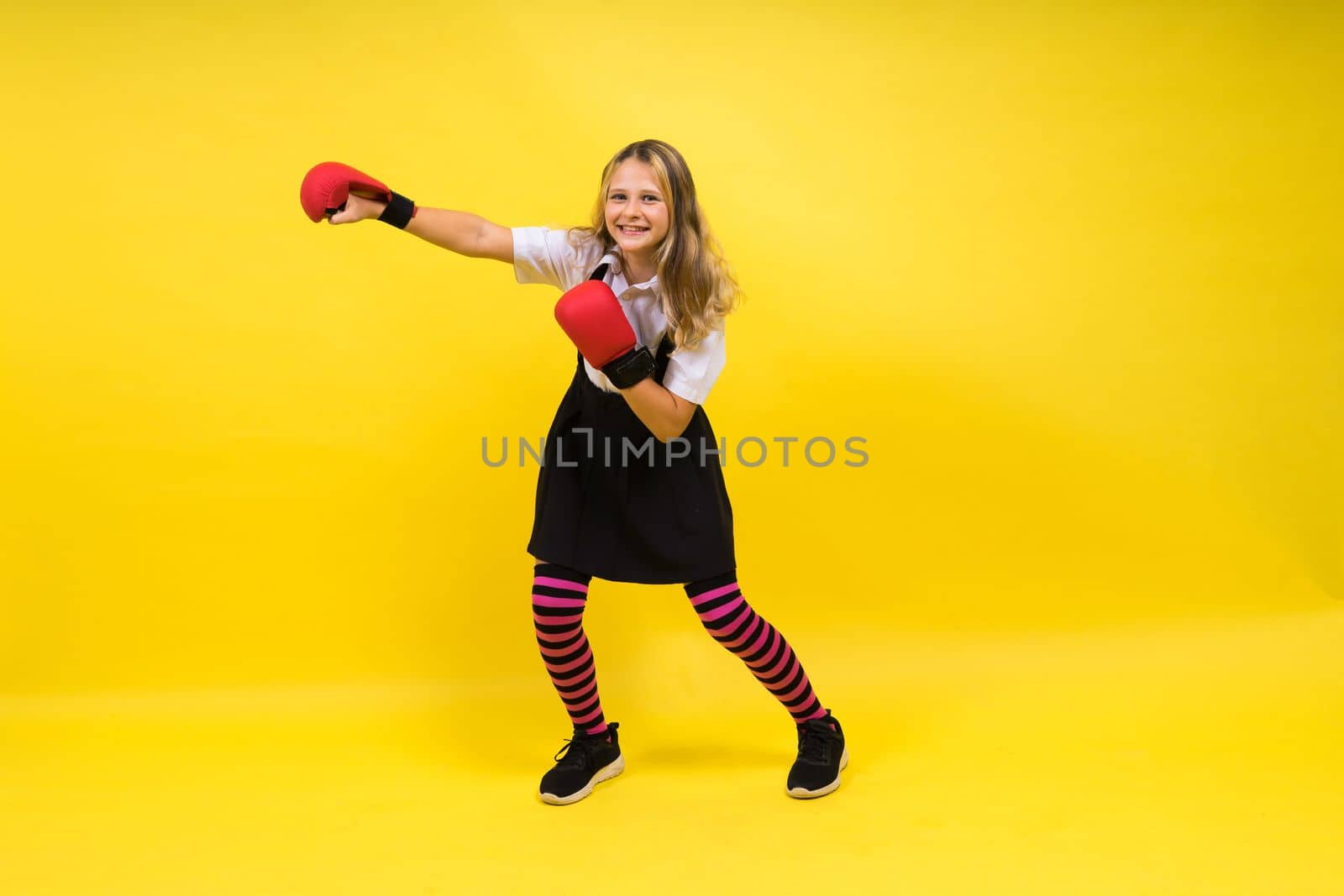 Little girl wearing red boxing gloves, studio shot, sport concept by Zelenin