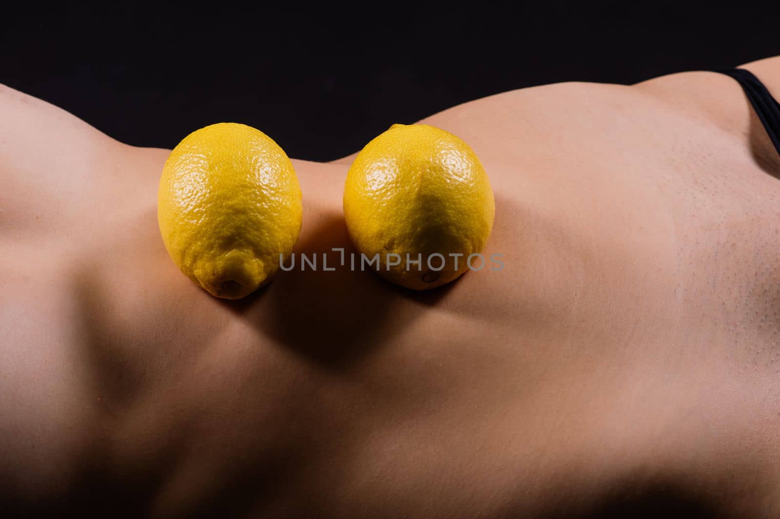 Young woman with cellulite problem and lemon on dark background, closeup by Zelenin