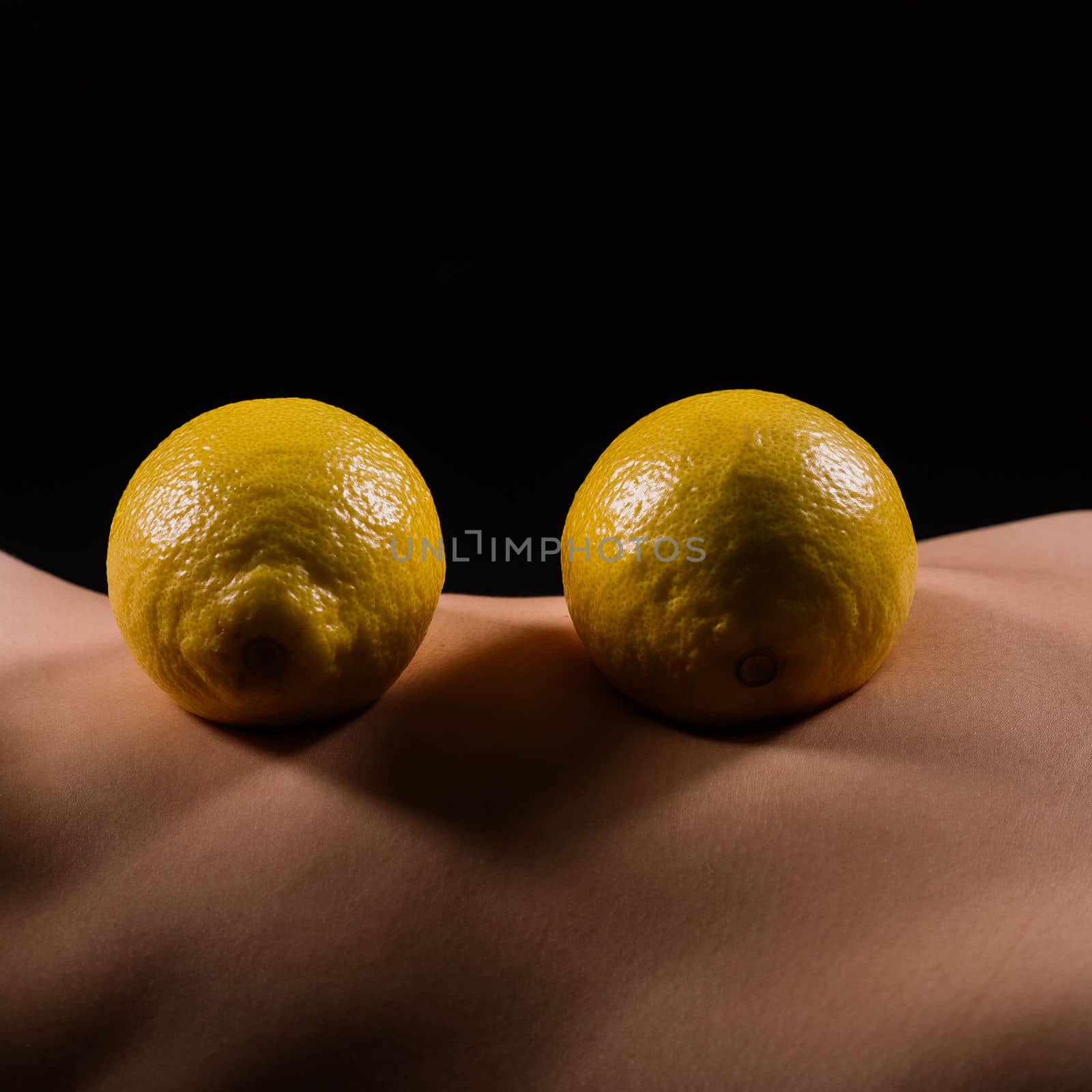 Young woman with cellulite problem and lemon on a dark background, closeup