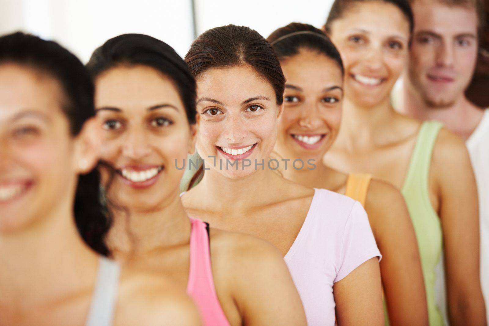 Feeling great after yoga class. Portrait of a positive-looking group of yoga students standing in a row and smiling at the camera