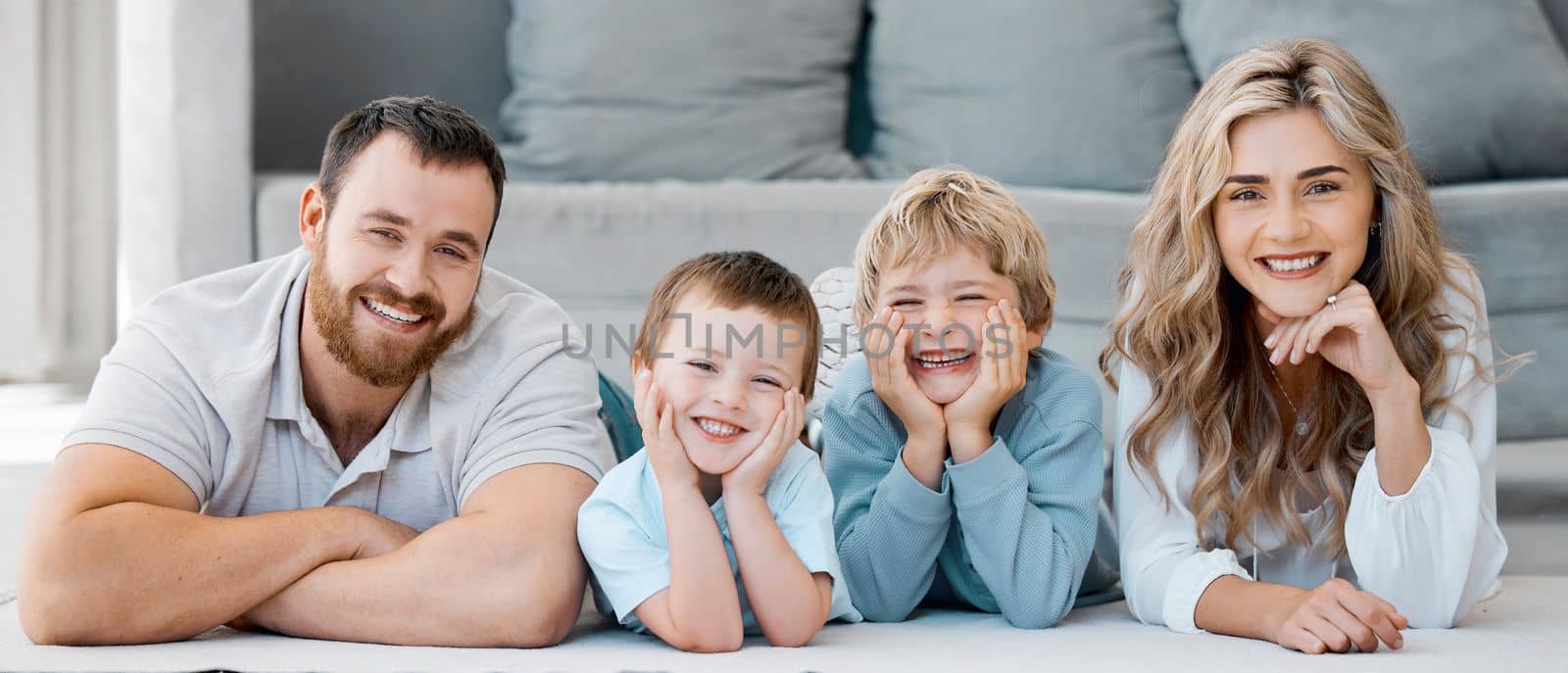 Portrait of smiling caucasian family of four lying and relaxing on the floor at home. Carefree loving parents bonding with cute little sons. Playful young boys spending quality time with mom and dad.