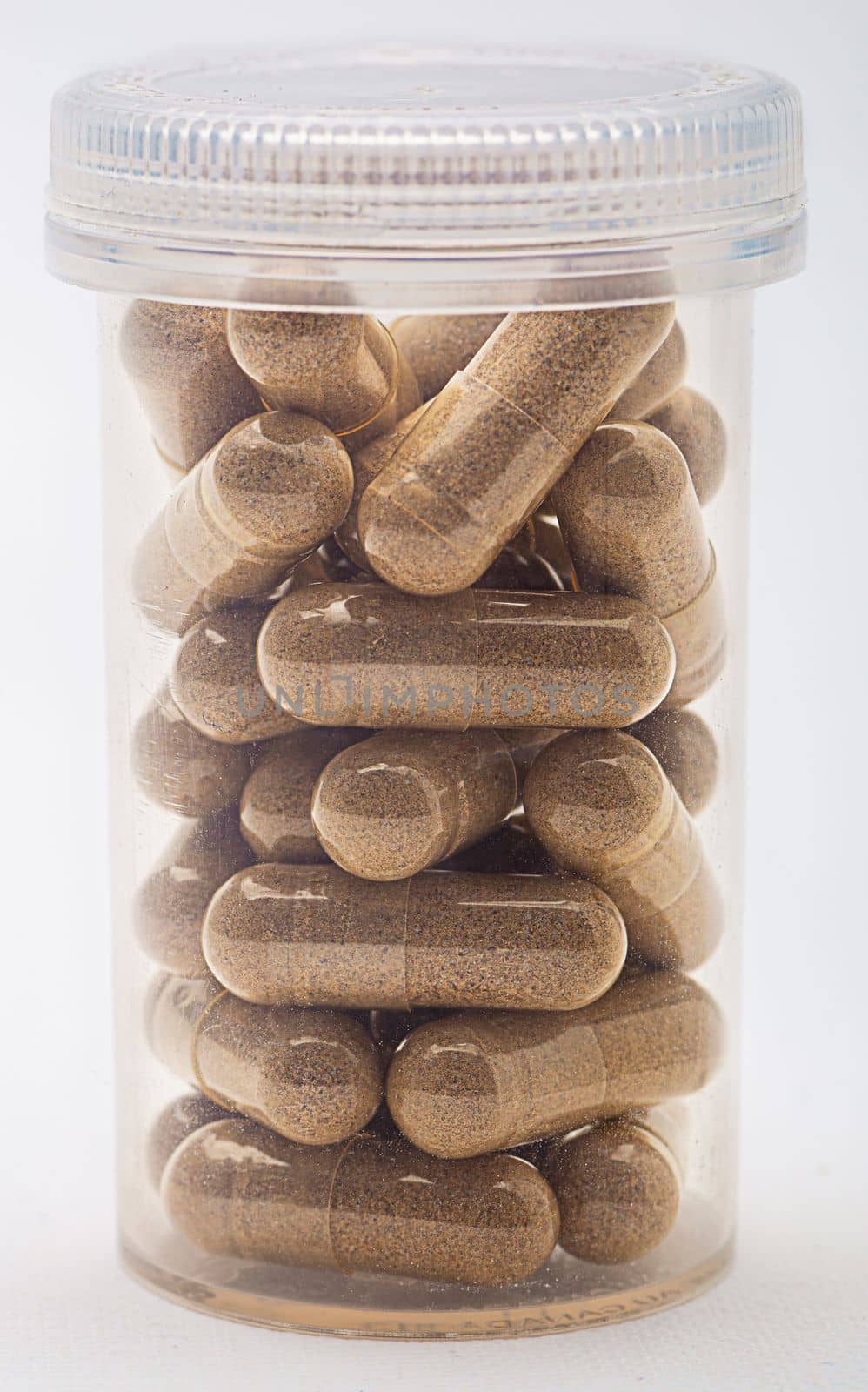 Isolated transparent bottle pill filled with transparent capsule containing brown natural supplement