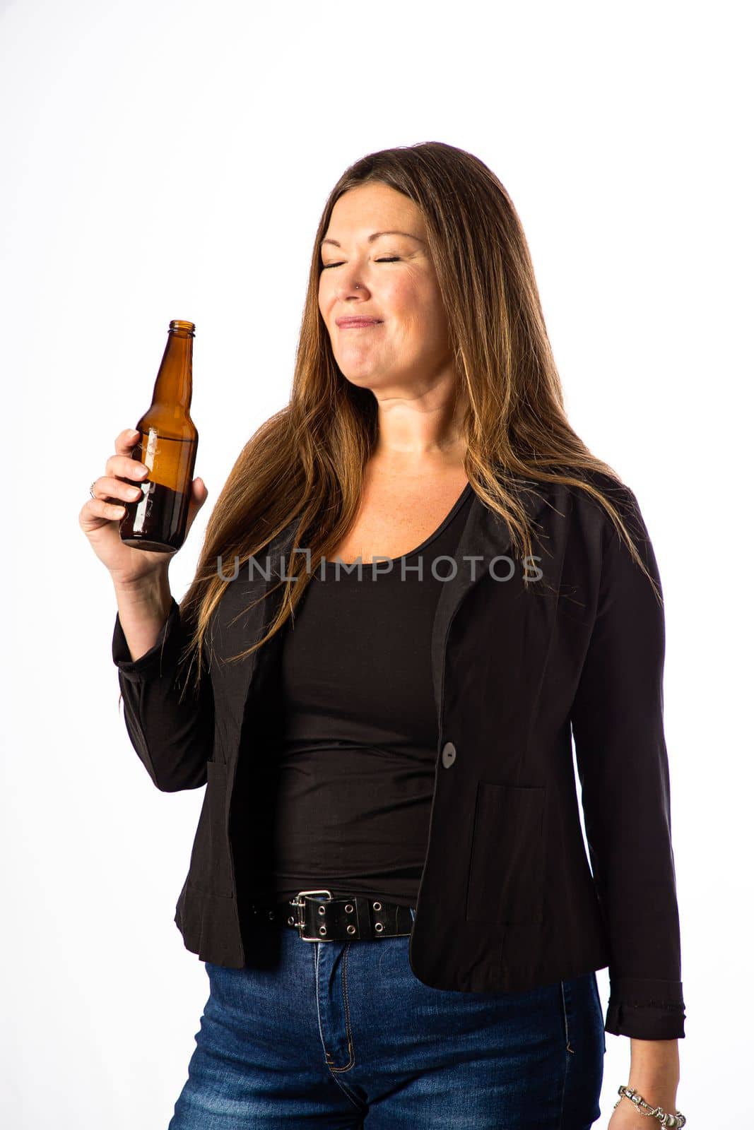 Isolated portrait of a forty year old woman in a sport coat holding a brown beer bottle, enjoying a drink
