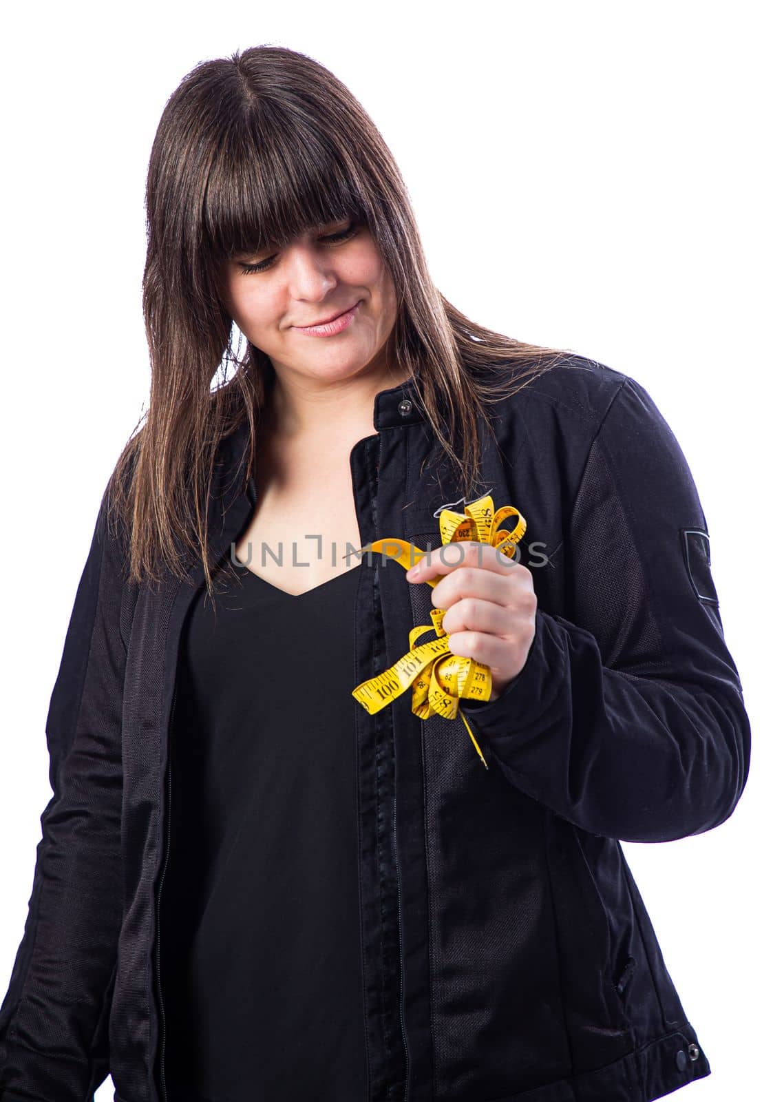 Isolated portrait of a forty year old woman, wearing a biker coat, holding a yellow mesuring tape