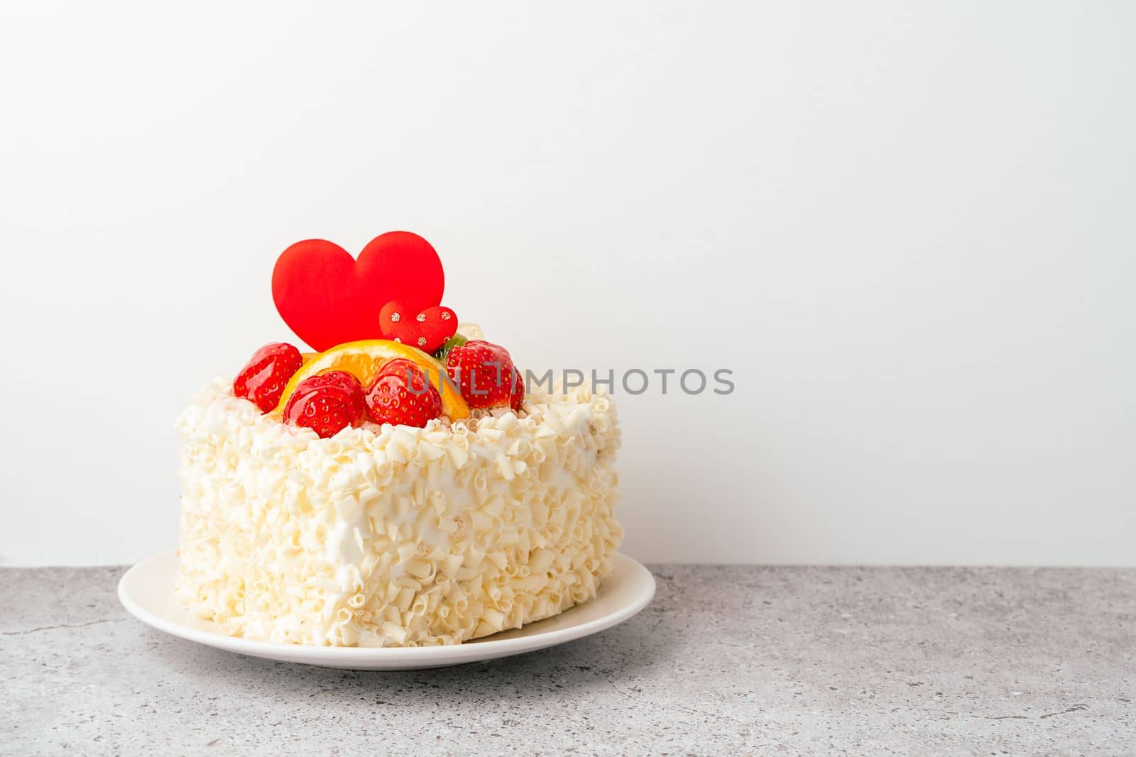 Valentine's Day cake with heart shape and fruits, strawberries with copy space. Birthday Cake for celebration. Valentine's Day and love concept. Present with love.
