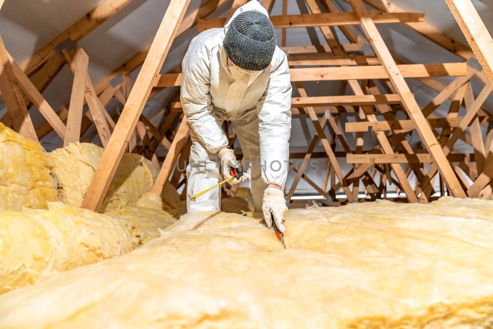 cutting glass wool when insulating the ceiling on the roof by Edophoto