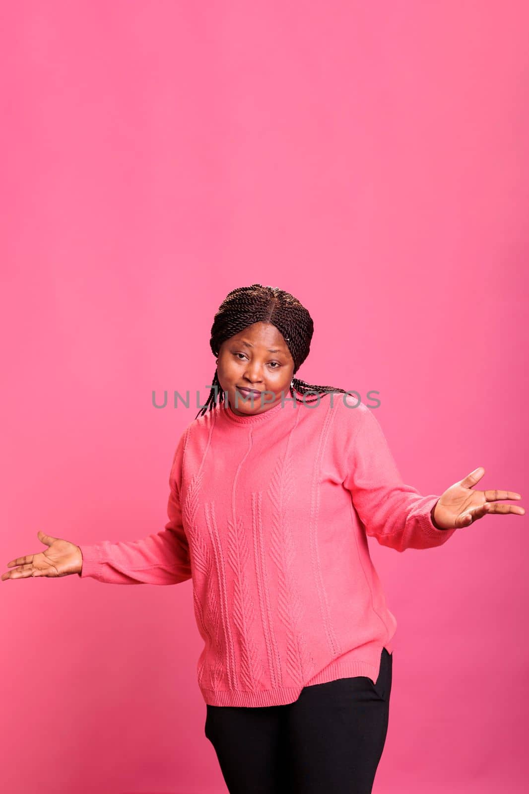 Smiling optimistic person with surprised reaction having fun in studio, feeling cheerful and relaxed in front of camera. Female model having positive energy and showing playful amusing symbol.