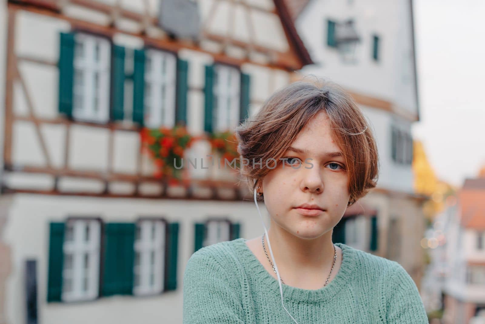 A Beautiful Girl Stands Against The Background Of The Window Of An Old European House. Tourism & Travel Concept. Nice Portrait Of A Young Woman, In Boho Style Outdoors In Fall Autumn Day. Caucasian Female Girl 12 Years Old.