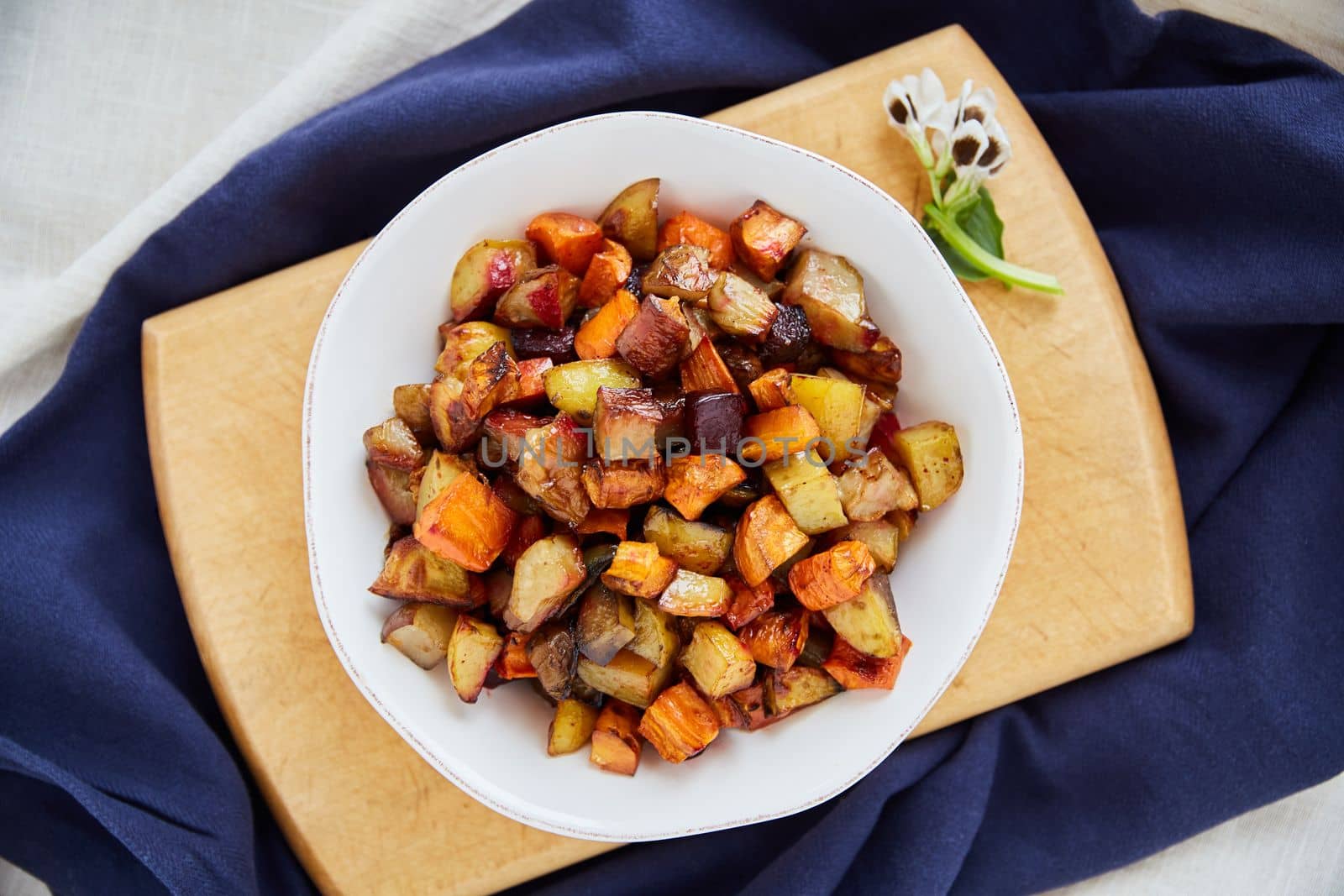 Eat more veggies. Overhead shot of roasted sweet potatoes in a white serving bowl. by YuriArcurs