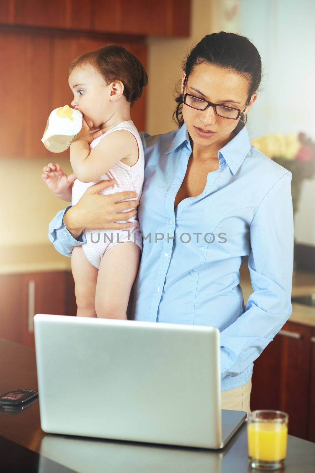 Motherhood is a fulltime job. a busy young mother at home with her baby. by YuriArcurs