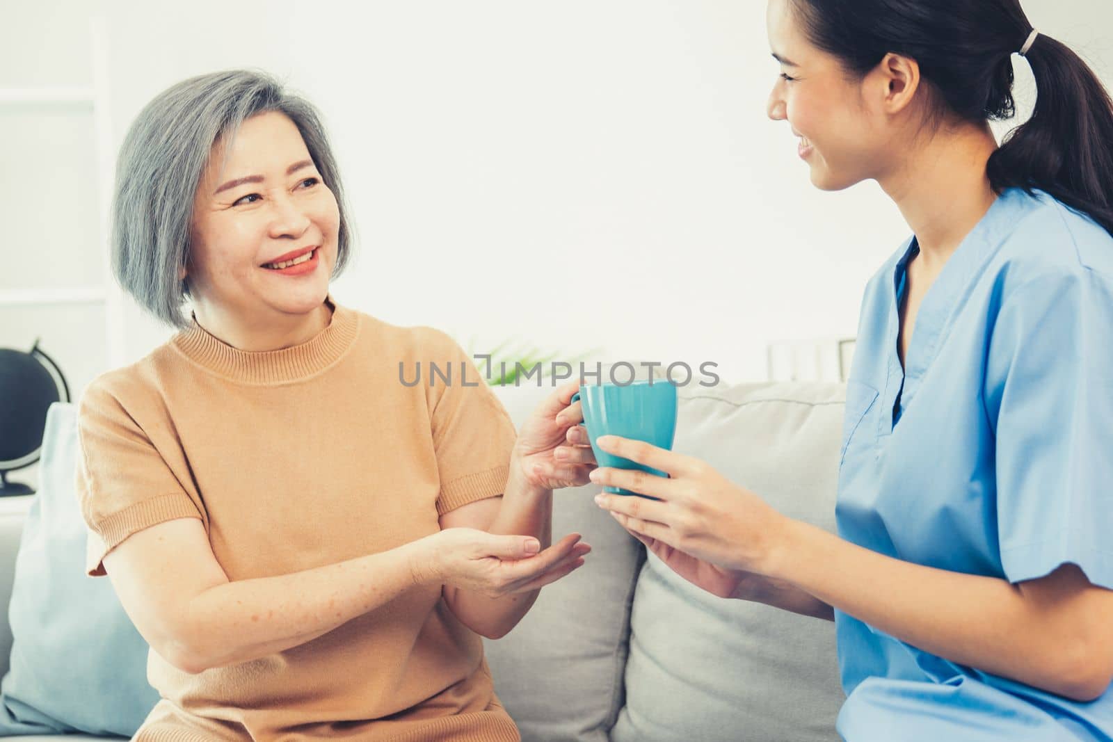Female care taker serving her contented senior patient with a cup of coffee. by biancoblue