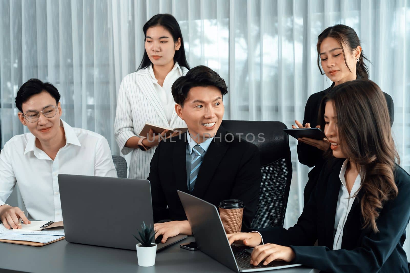 Harmony in office concept as business people analyzing dashboard paper together in workplace. Young colleagues give ideas at manager desk for discussion or strategy planning about project.