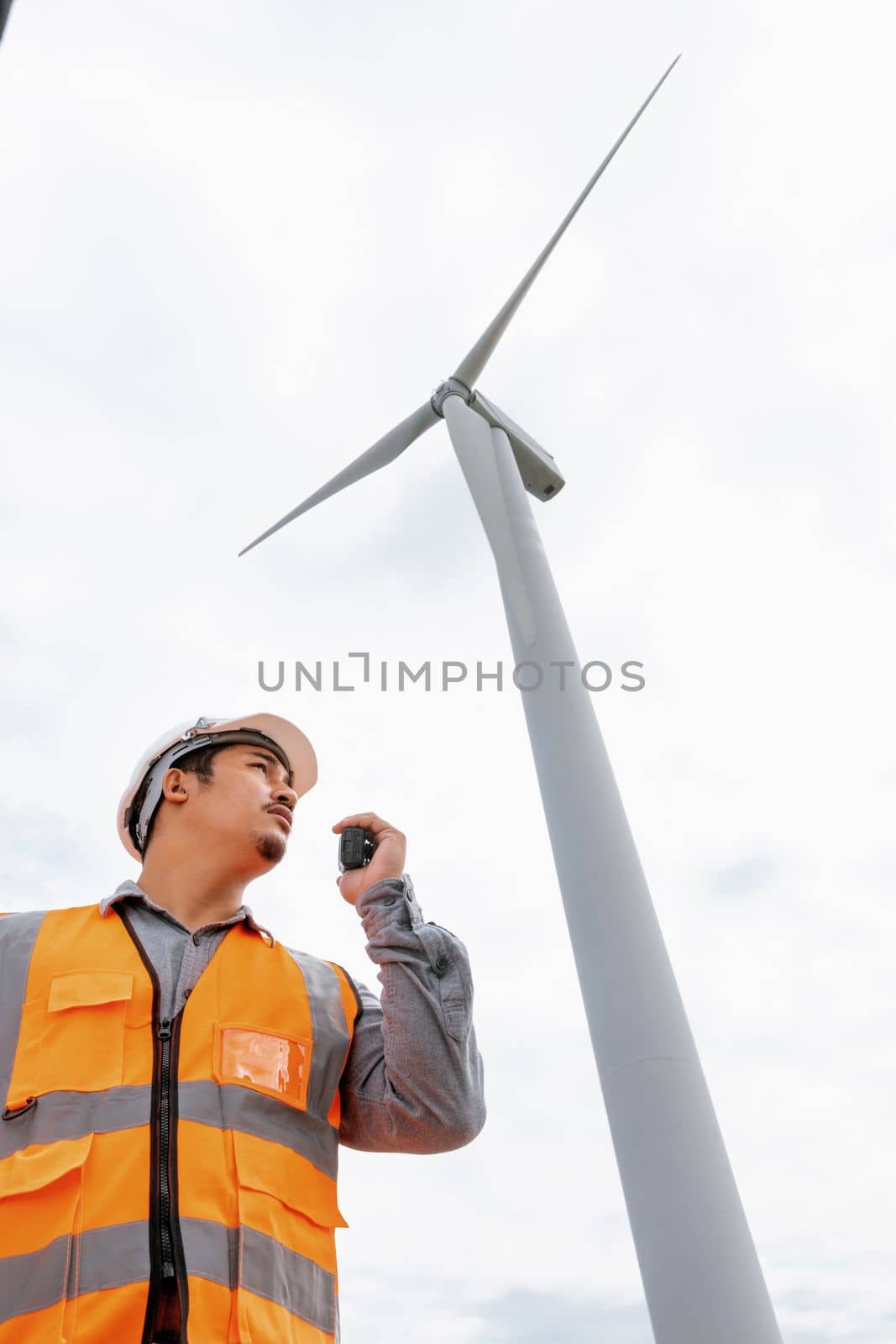 Progressive concept of engineer working in the wind farm atop of the mountain. by biancoblue