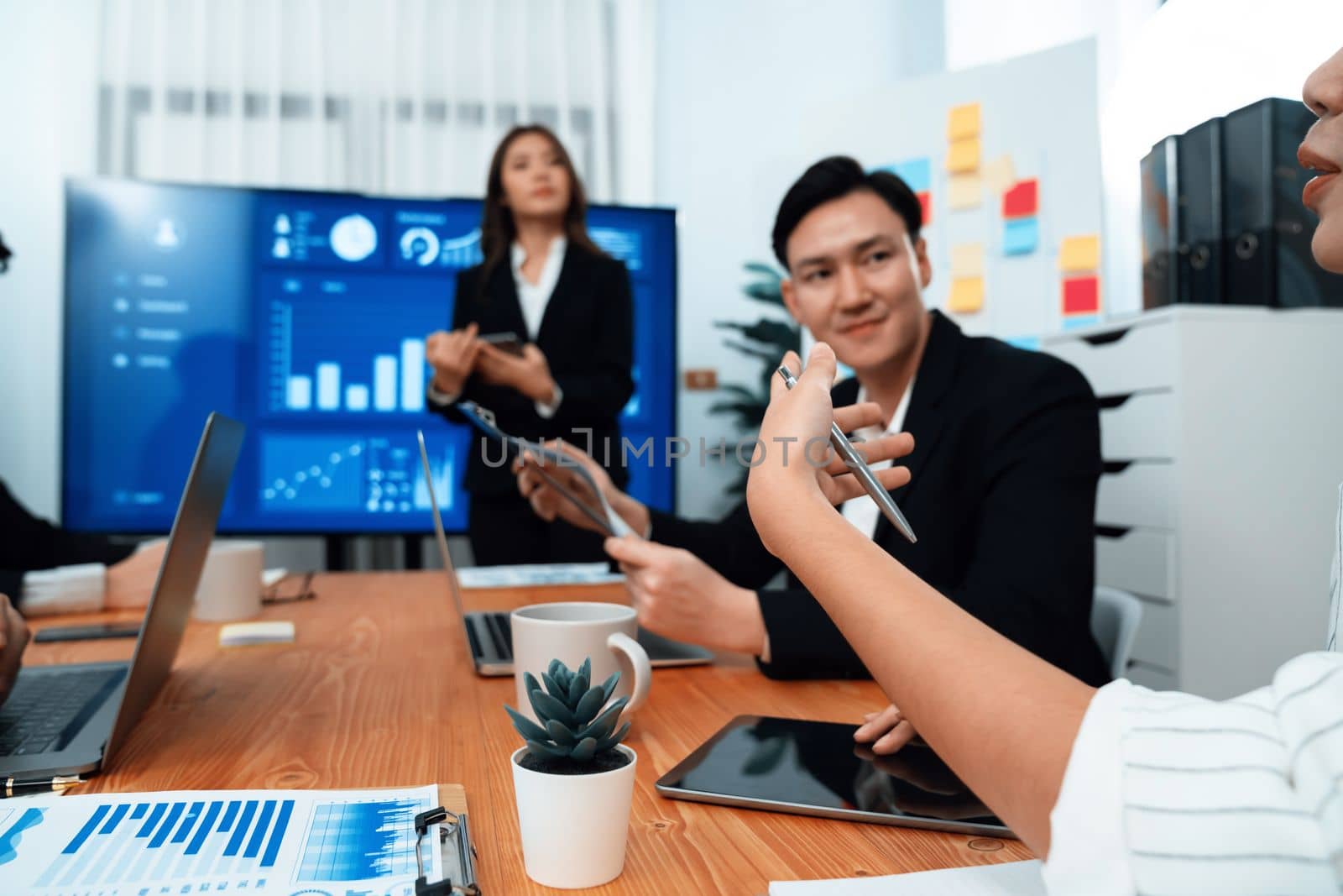 Confidence and young asian businesswoman give presentation on financial business strategy in dashboard report display on screen to colleagues in conference room meeting as harmony in workplace concept