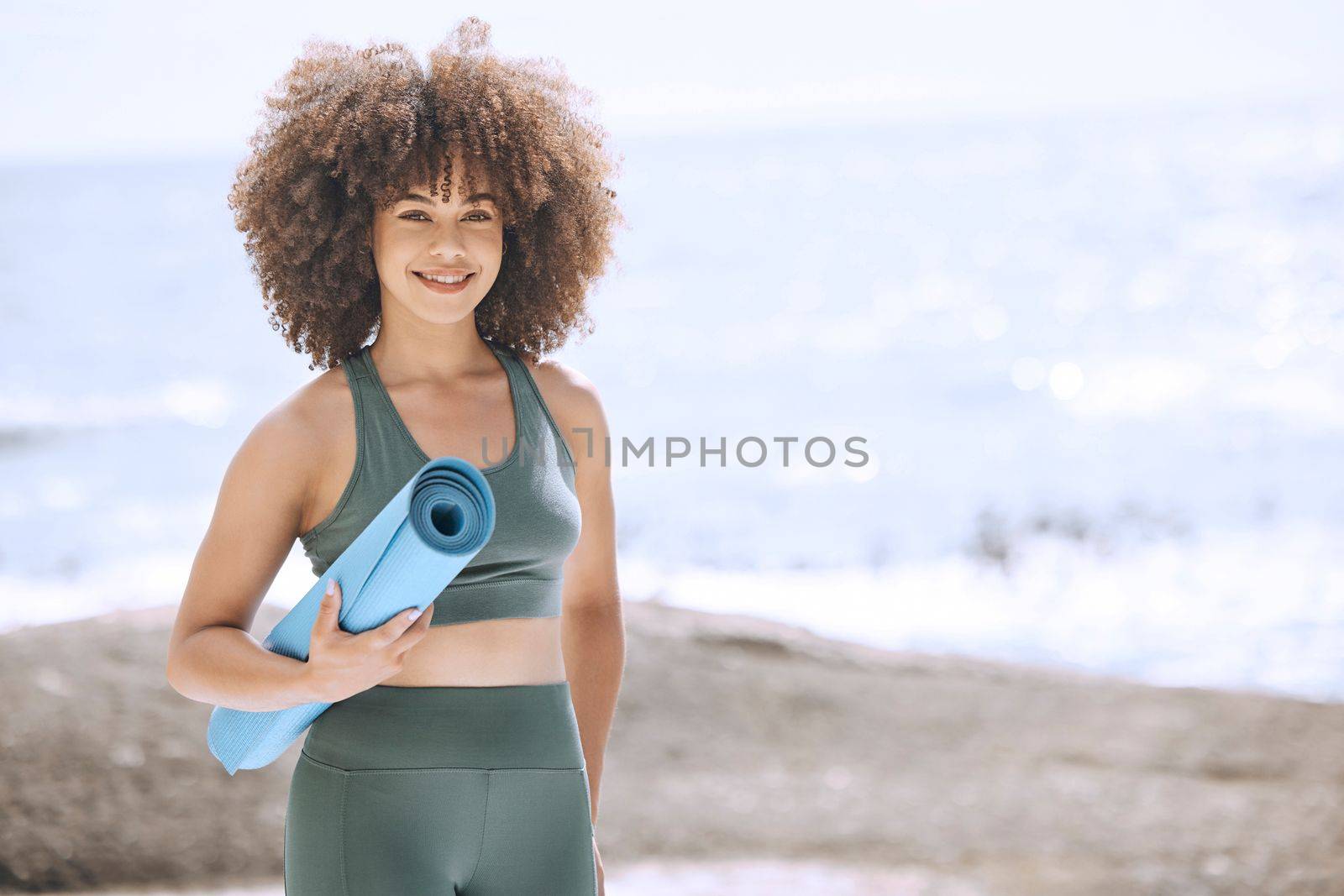 Yoga, fitness and beach with a black woman athlete by the sea with her exercise mat for a workout. Nature, water and health with a female yogi exercising for wellness, zen or mental health outside.