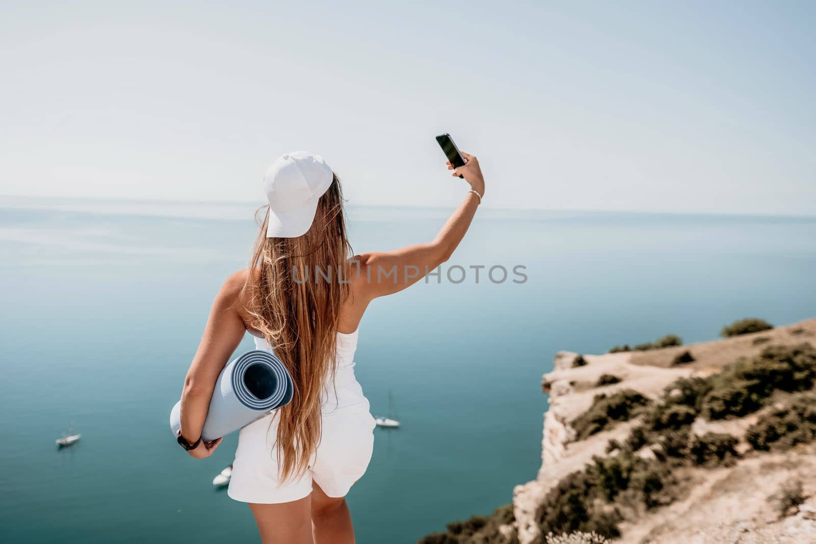Young woman with black hair, fitness instructor in pink sports leggings and tops, doing pilates on yoga mat with magic pilates ring by the sea on the beach. Female fitness daily yoga concept
