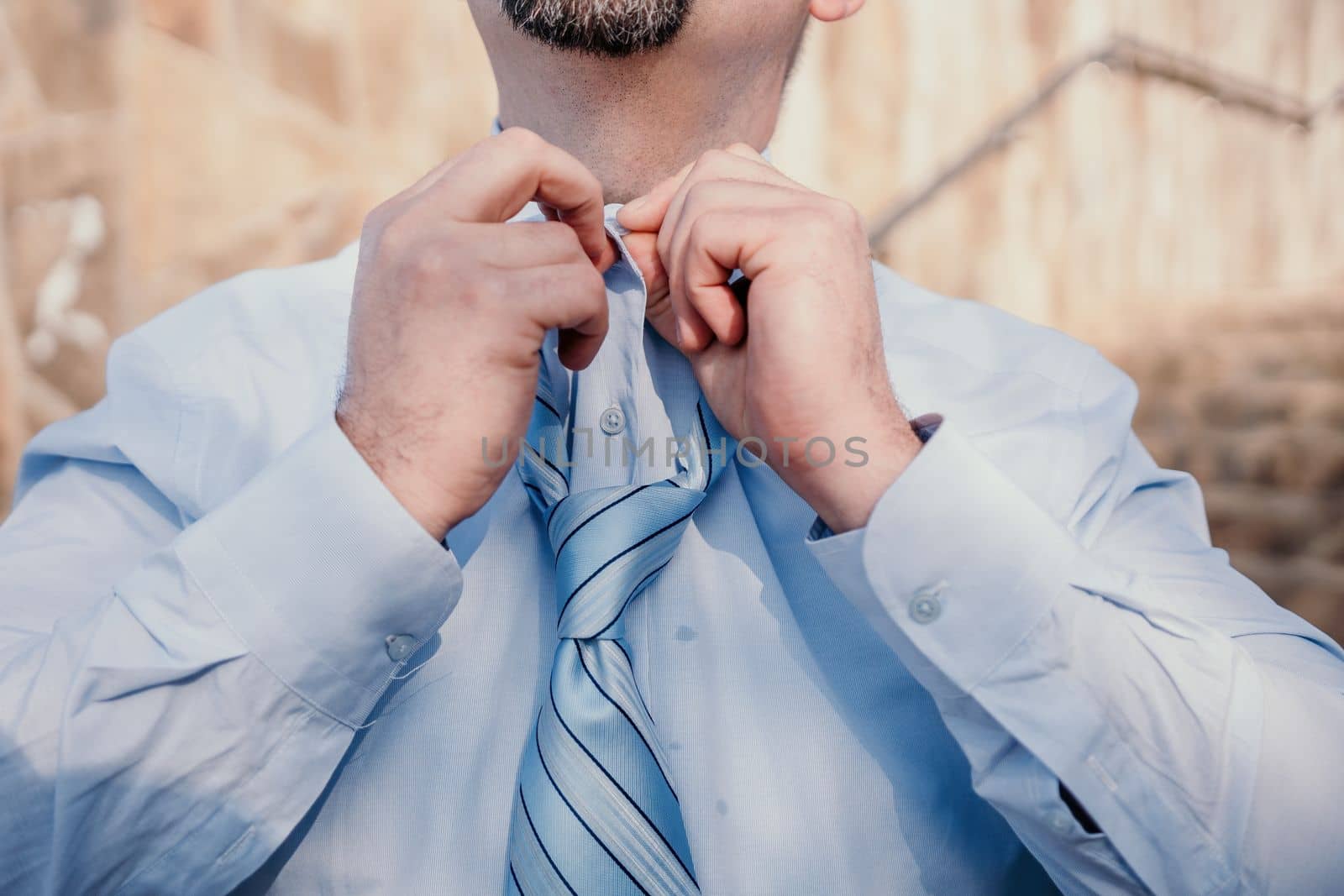 Close up of Man Adjusting Tie of Suit. Businessman in white shirt straightens his tie, close-up.