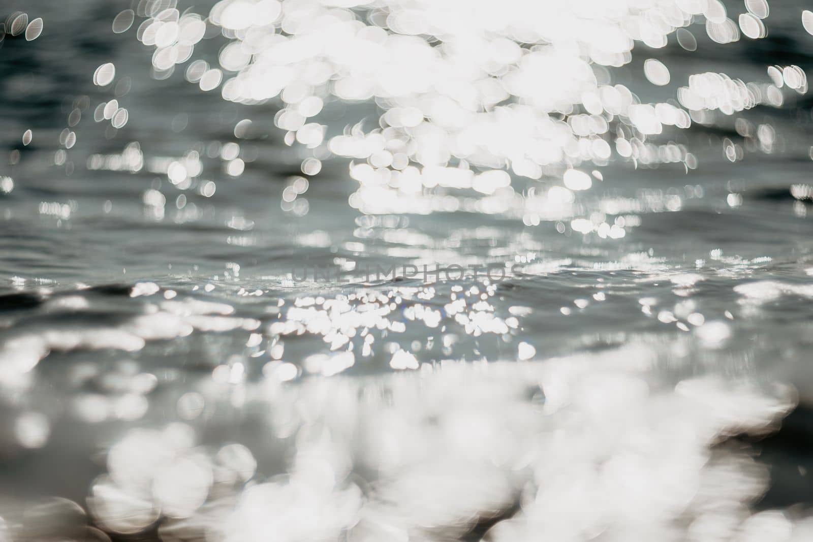 Abstract sea summer ocean sunset nature background. Sound of small waves on golden water surface in motion blur with golden bokeh lights from sun. Holiday, vacation and recreational concept.