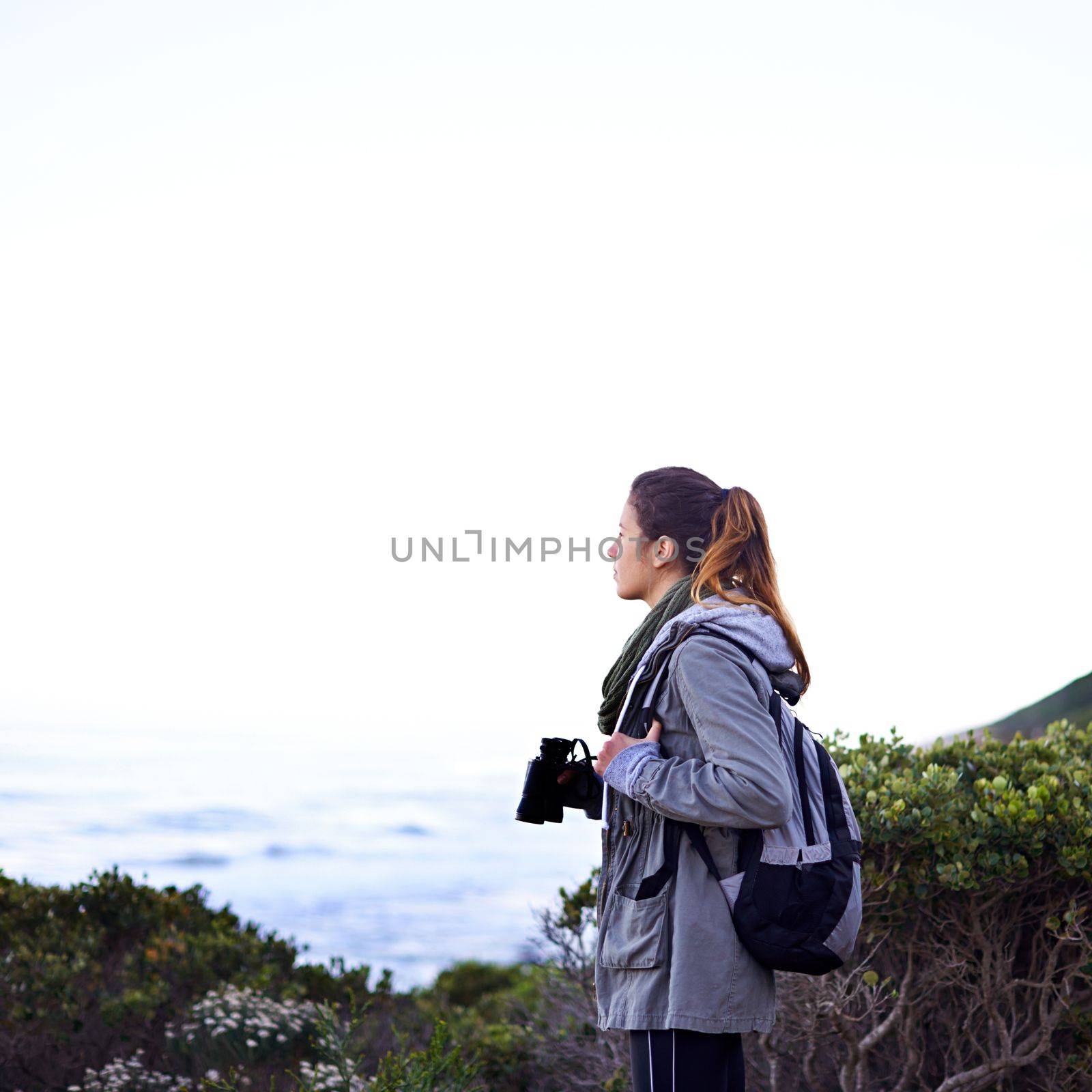 Appreciating the beauty of nature. a young woman using binoculars while out hiking