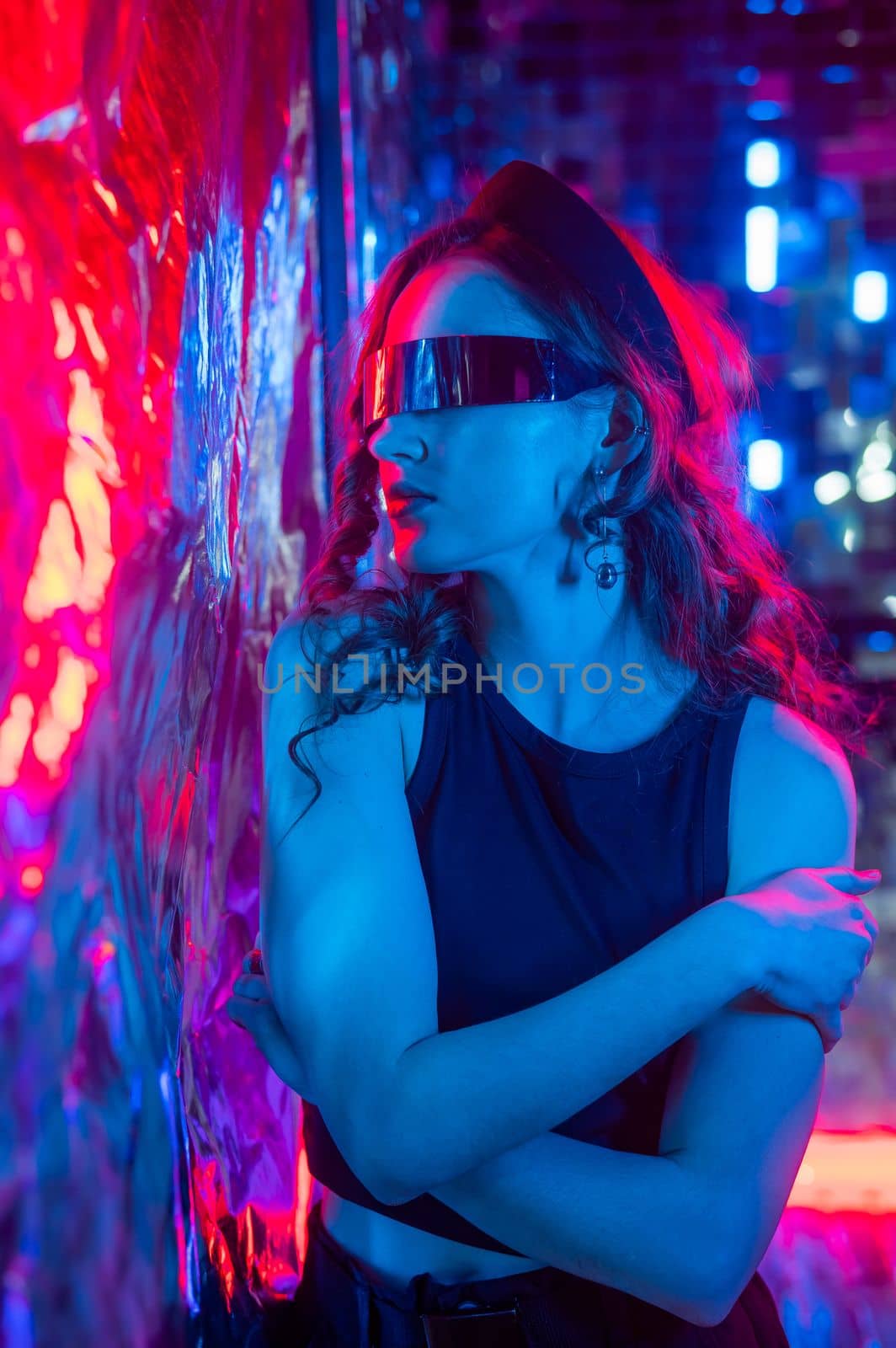 Close-up portrait of caucasian woman in sunglasses in neon light against foil wall