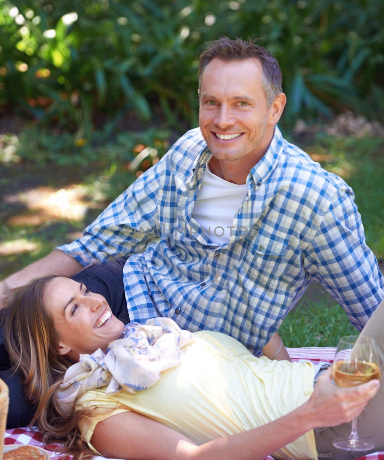 Enjoying a romantic picnic outdoors. a married couple enjoying a picnic outdoors. by YuriArcurs