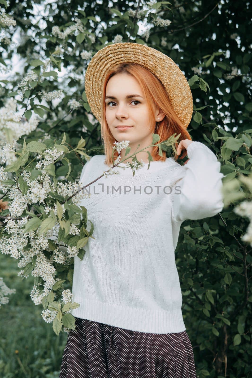 Portrait of a woman in a straw hat in a cherry blossom. Free outdoor recreation, spring blooming garden