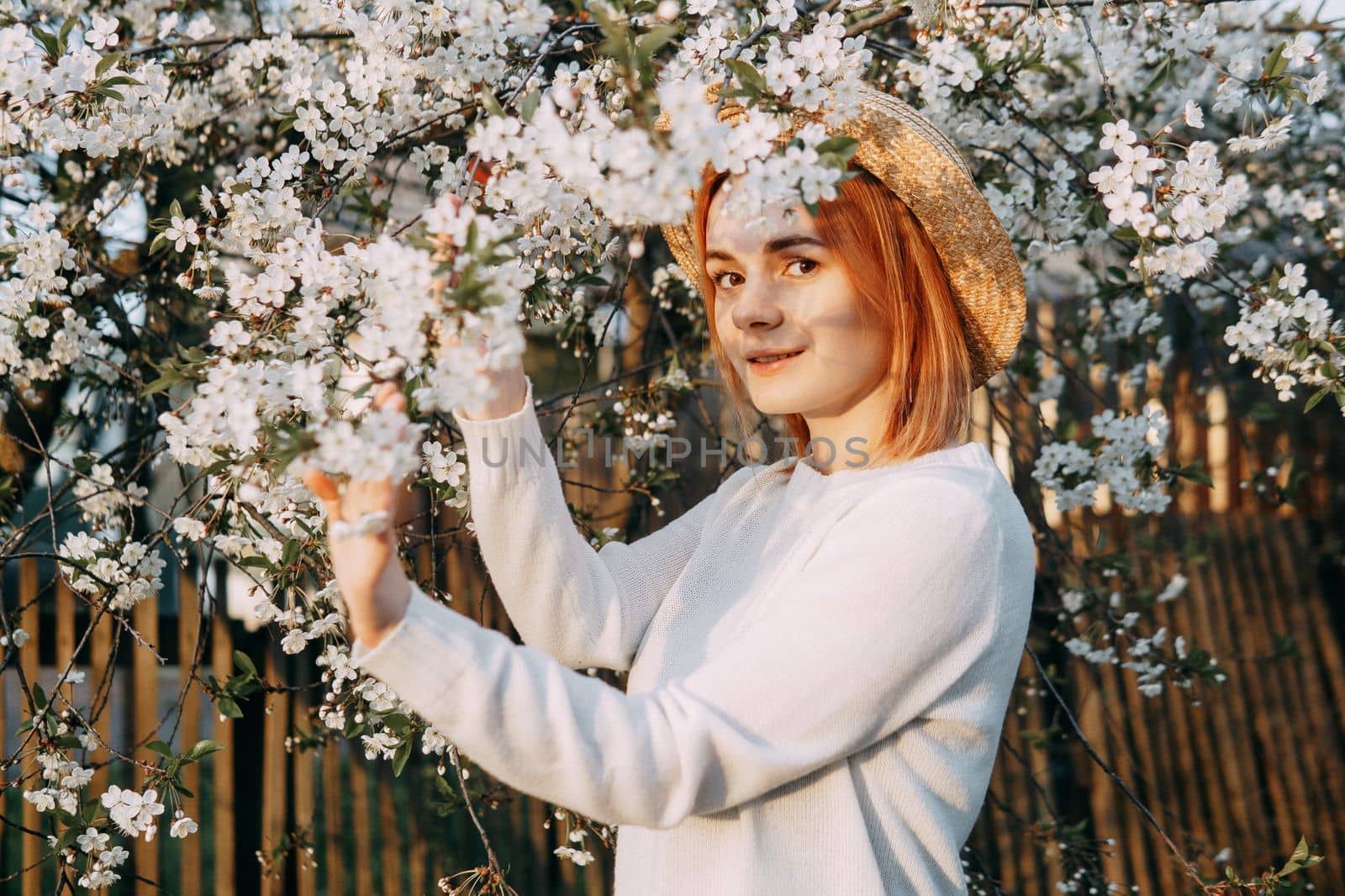 Portrait of a woman in a straw hat in a cherry blossom. Free outdoor recreation, spring blooming garden