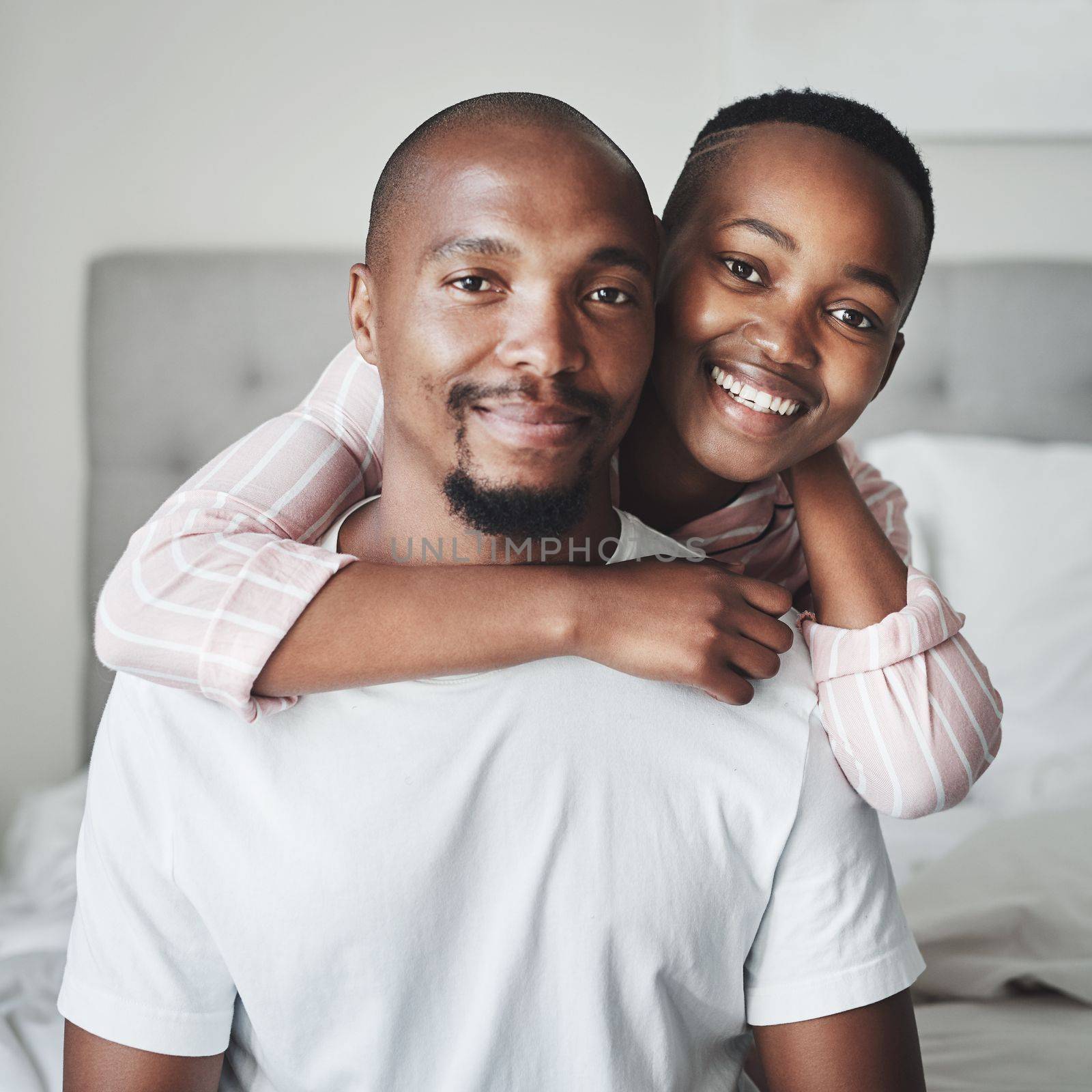 Portrait, love and black couple in bedroom, smile and romance for Valentines day, affection and hug. Romantic, man and woman embrace on bed, loving and bonding on weekend break and relax together.