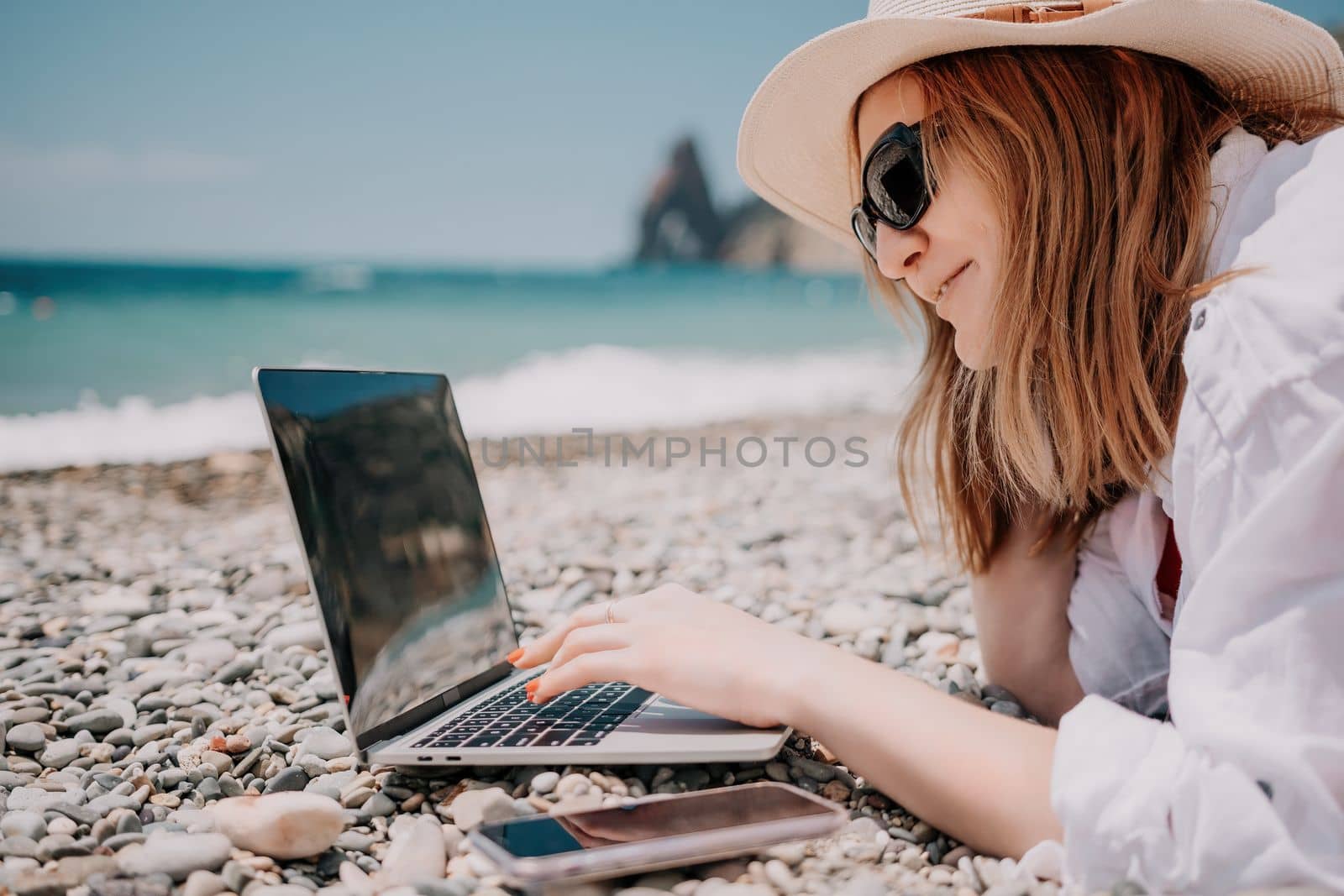 Woman sea laptop. Business woman in yellow hat working on laptop by sea. Close up on hands of pretty lady typing on computer outdoors summer day. Freelance, digital nomad, travel and holidays concept