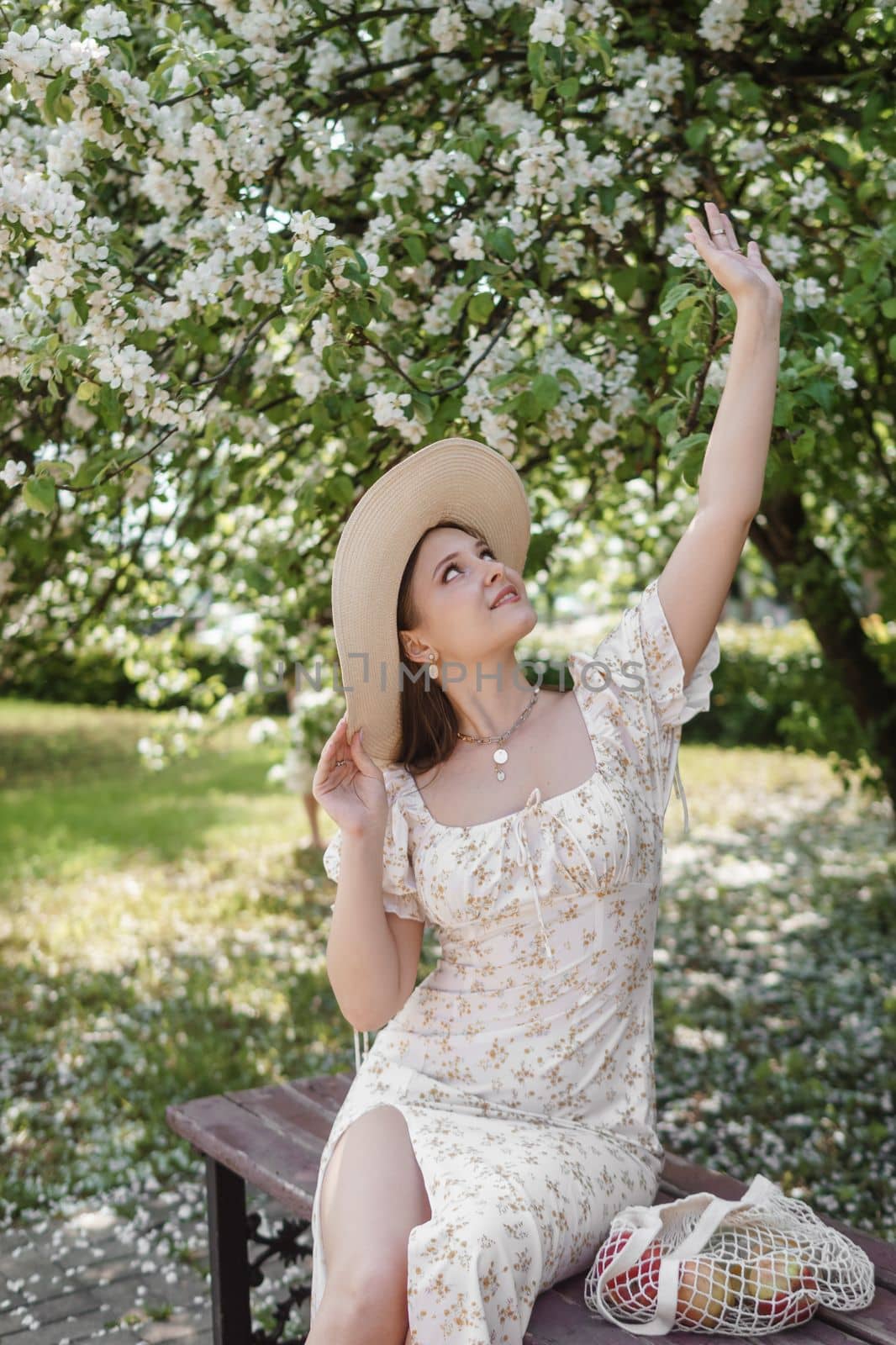 An attractive long-haired woman walks in the spring in the park of blooming apple trees. Spring portrait of a woman