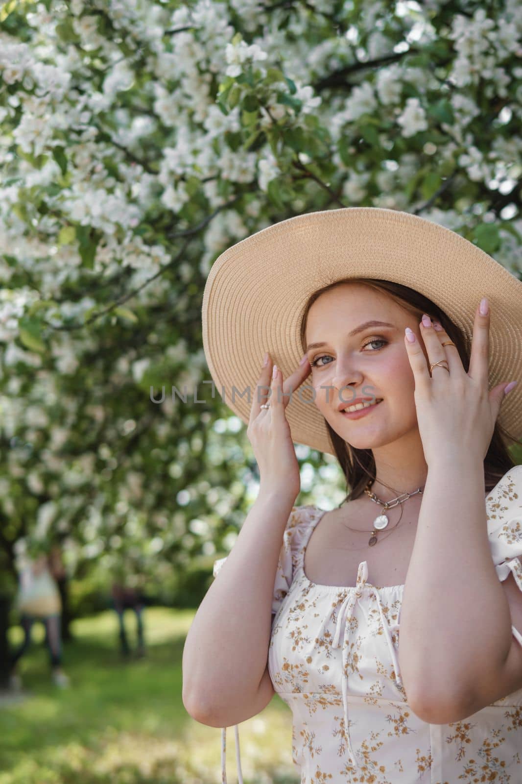 An attractive long-haired woman walks in the spring in the park of blooming apple trees. Spring portrait of a woman