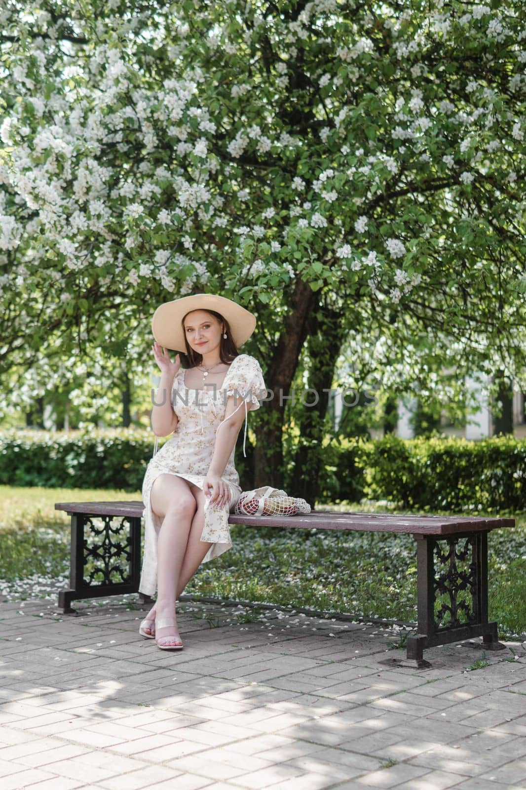 An attractive long-haired woman walks in the spring in the park of blooming apple trees. Spring portrait of a woman