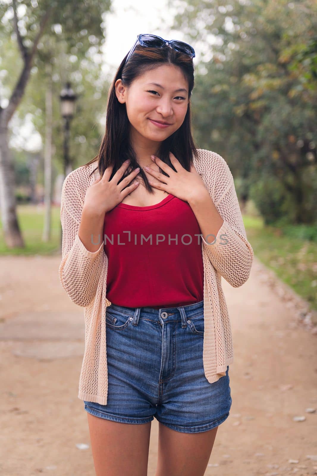 vertical portrait of a beautiful young asian woman looking at camera in the park, concept of youth and beauty