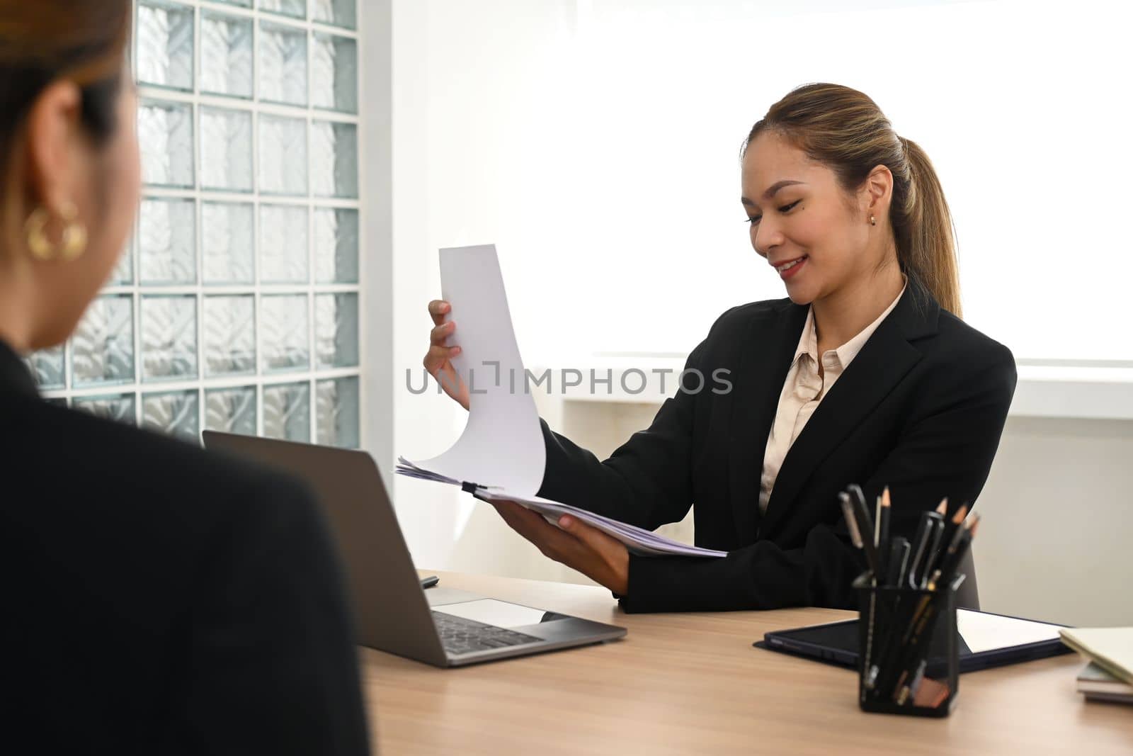 Smiling female hr manager considering application female candidate during job interview. Employment and recruitment concept by prathanchorruangsak