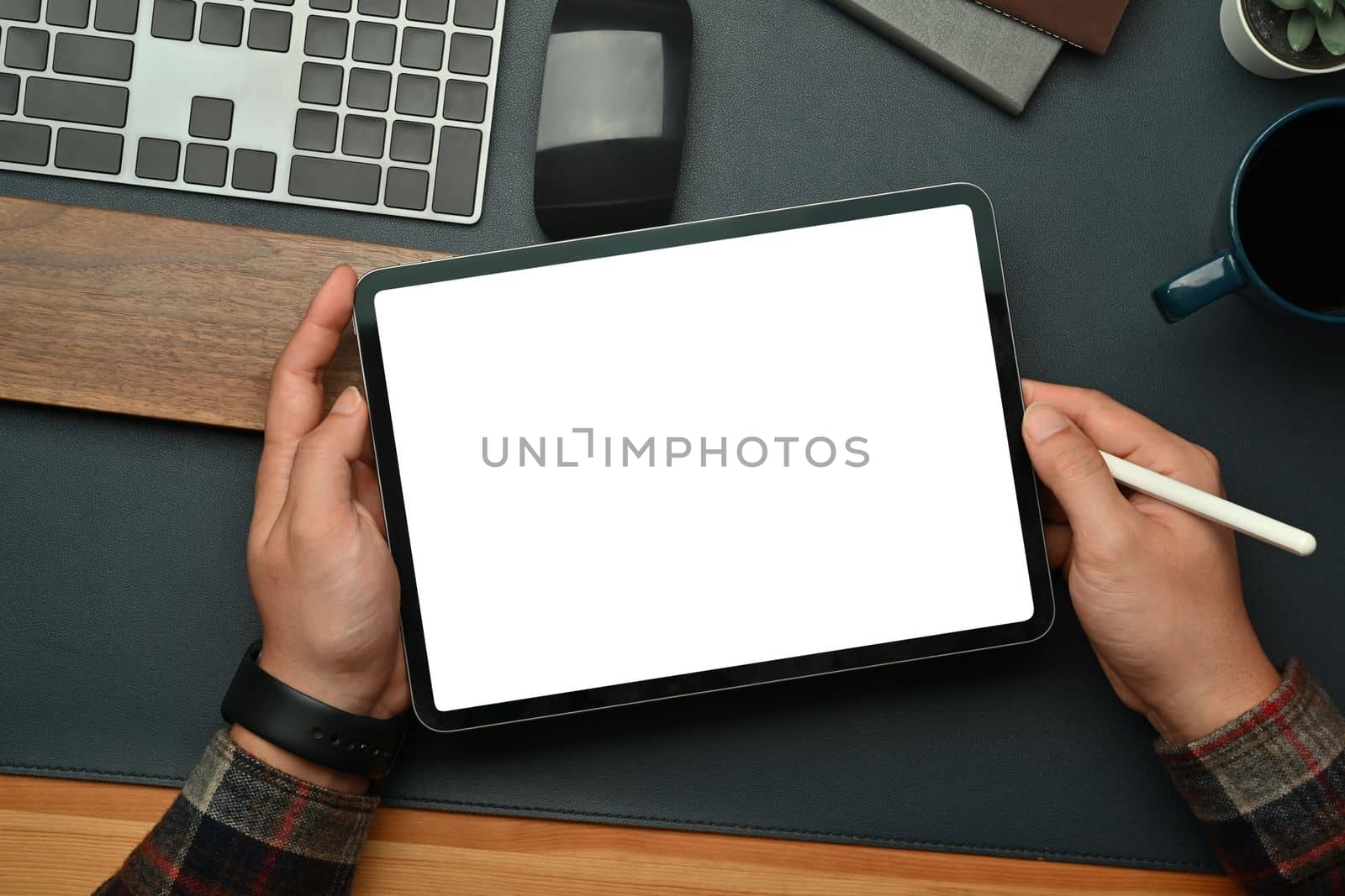 Above man hands holding digital tablet with blank screen over black leather at workspace. Empty screen for your advertise design by prathanchorruangsak