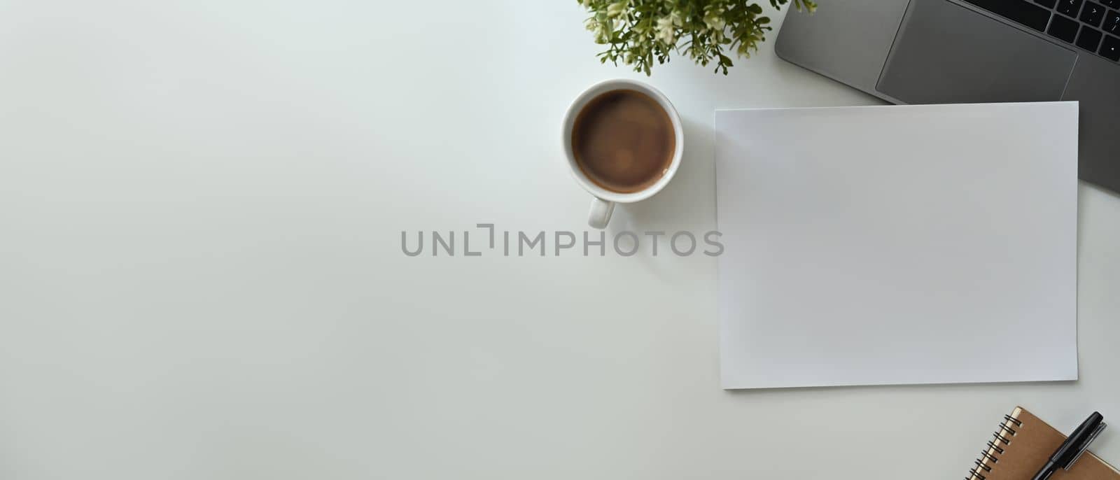 Flat lay, Top view of blank paper, cup of coffee, laptop and notebook on office desk. Copy space for advertise text by prathanchorruangsak