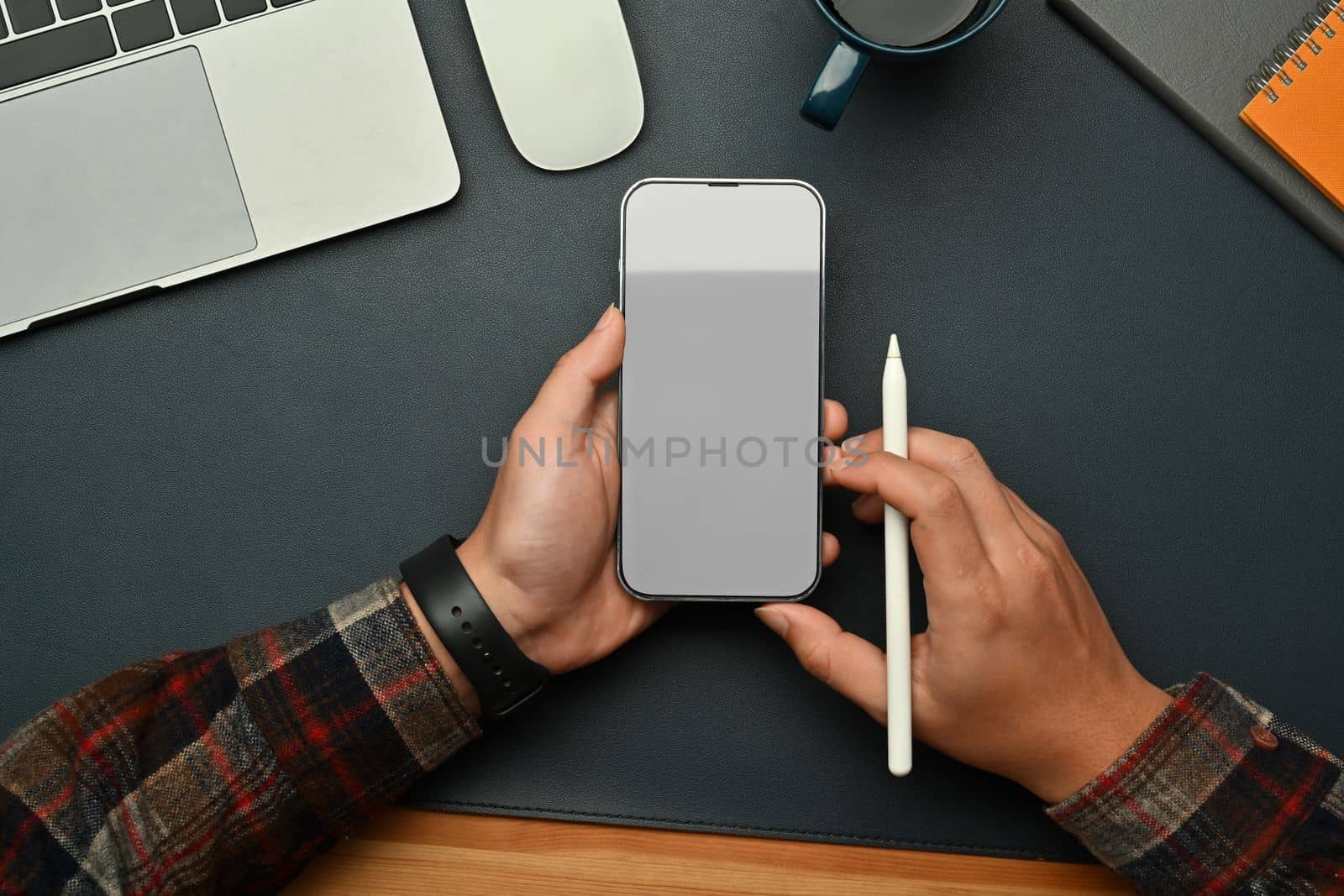 Man hands holding mock up smart phone with blank screen over black leather.