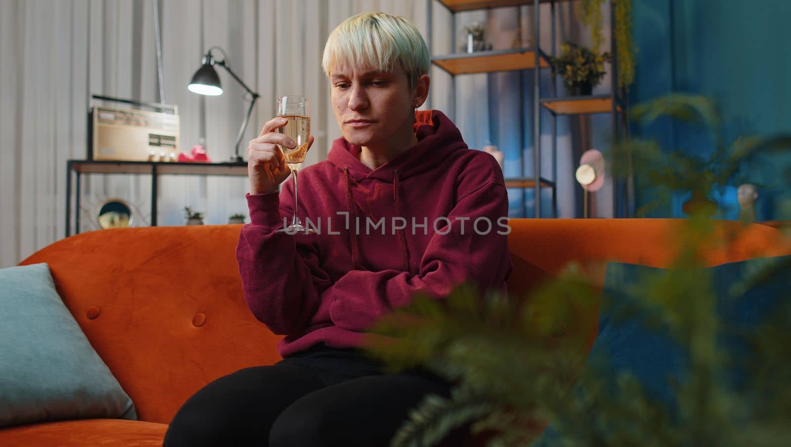 Sad woman girl with short hair sitting at home looks pensive of unrequited love, suffers from unfair situation, drinking champagne. Problem, break up, depressed feeling bad annoyed, burnout bankruptcy