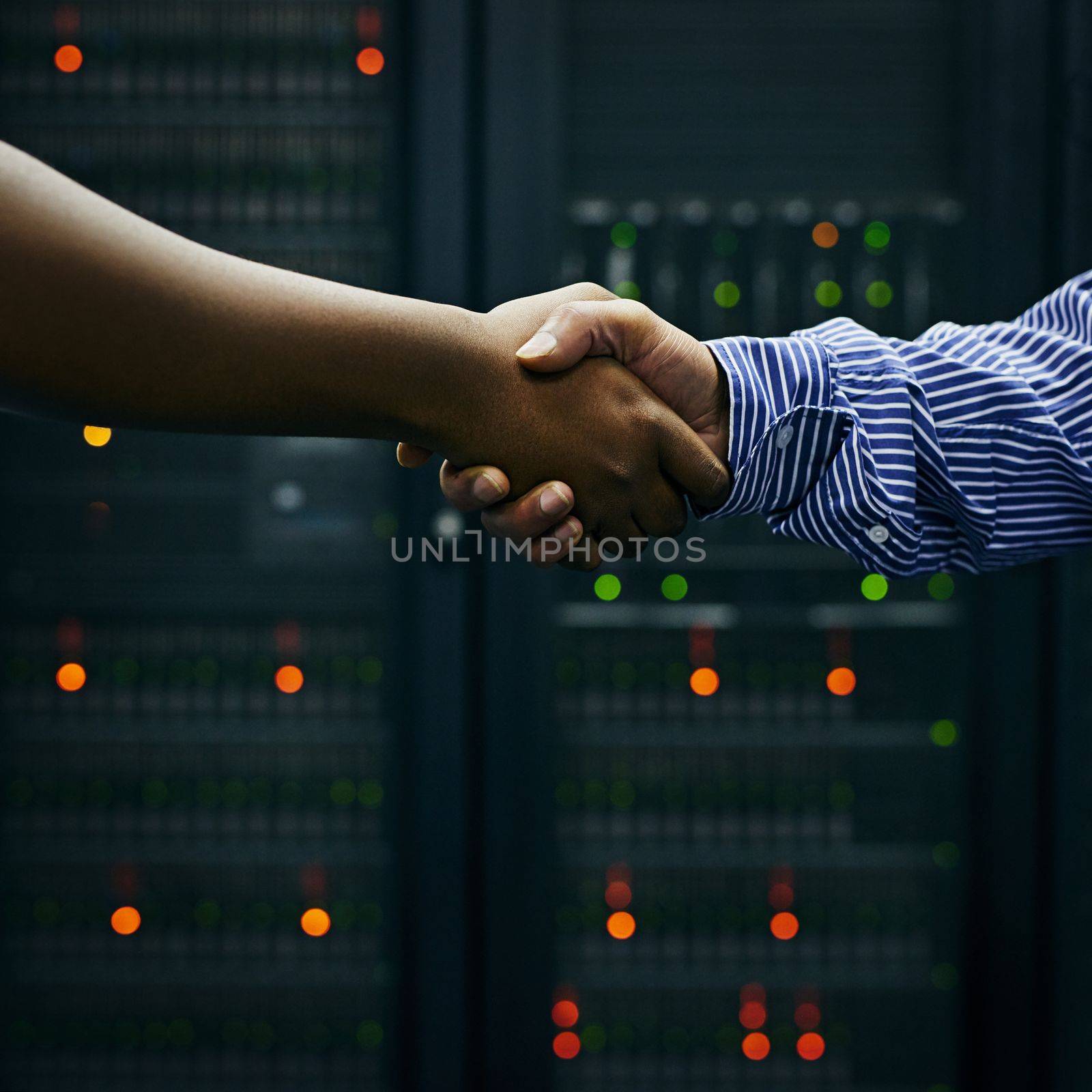 Making deals in the data center. two men shaking hands in a data center. by YuriArcurs
