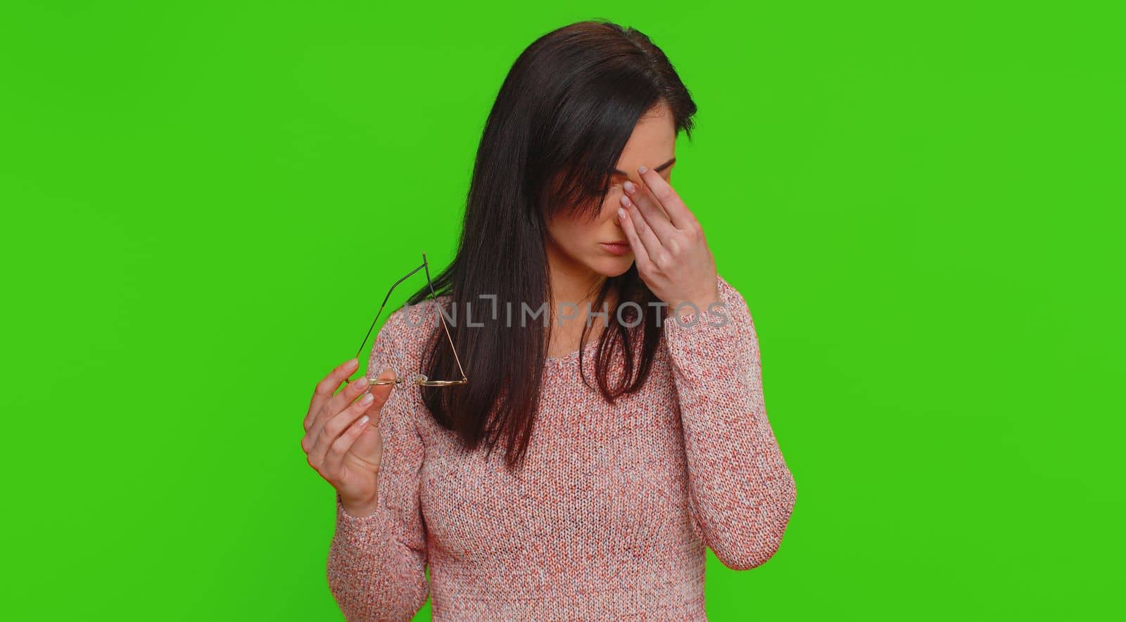 Exhausted tired pretty woman takes off glasses, feels eyes hard pain, being overwork burnout from long hours working, headache. Unhappy sad young adult girl isolated on green chroma key background