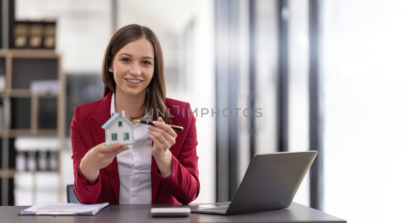 Woman holding white house model in hand.Mortgage loan approval home loan and insurance concept by nateemee