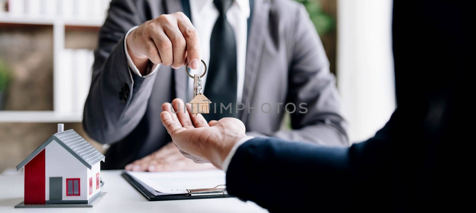 Real estate agents agree to buy a home and give keys to clients at their agency's offices. Concept agreement by wichayada