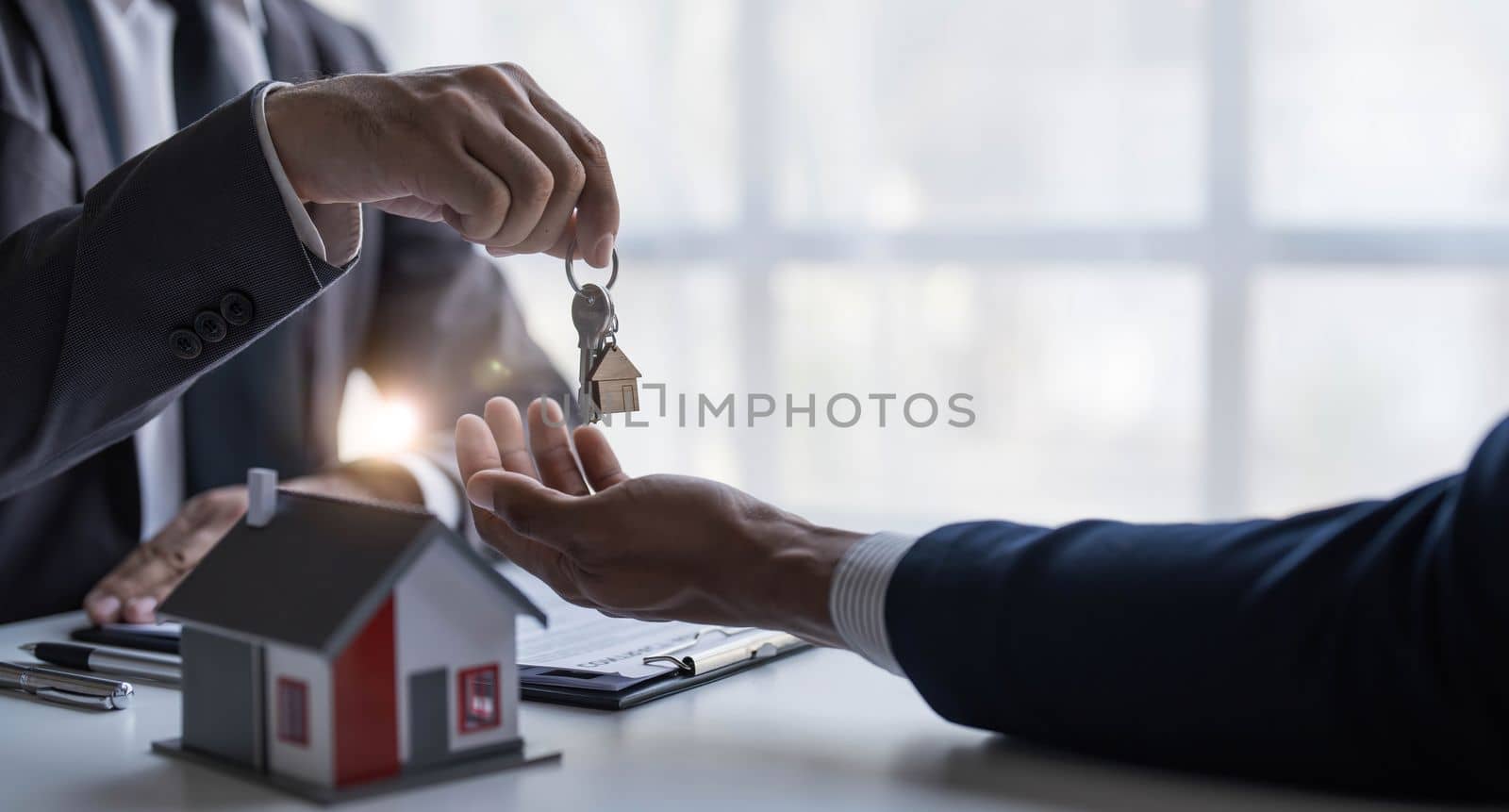 Real estate agents agree to buy a home and give keys to clients at their agency's offices. Concept agreement by wichayada