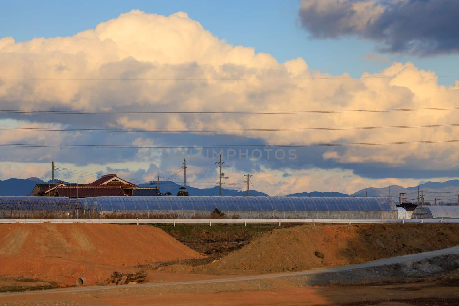 Mounds of earth by ramp to construction site under billowing clouds. High quality photo