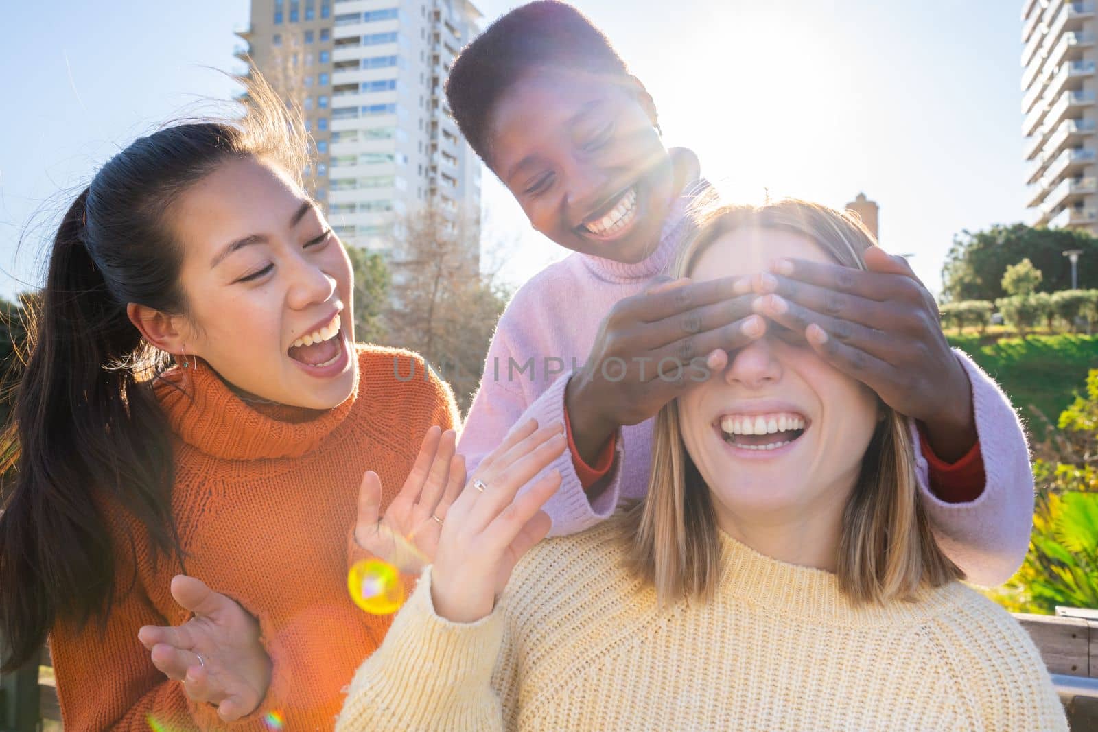 Happy real people. Female friends having fun together covering each other eyes for a surprise. High quality photo