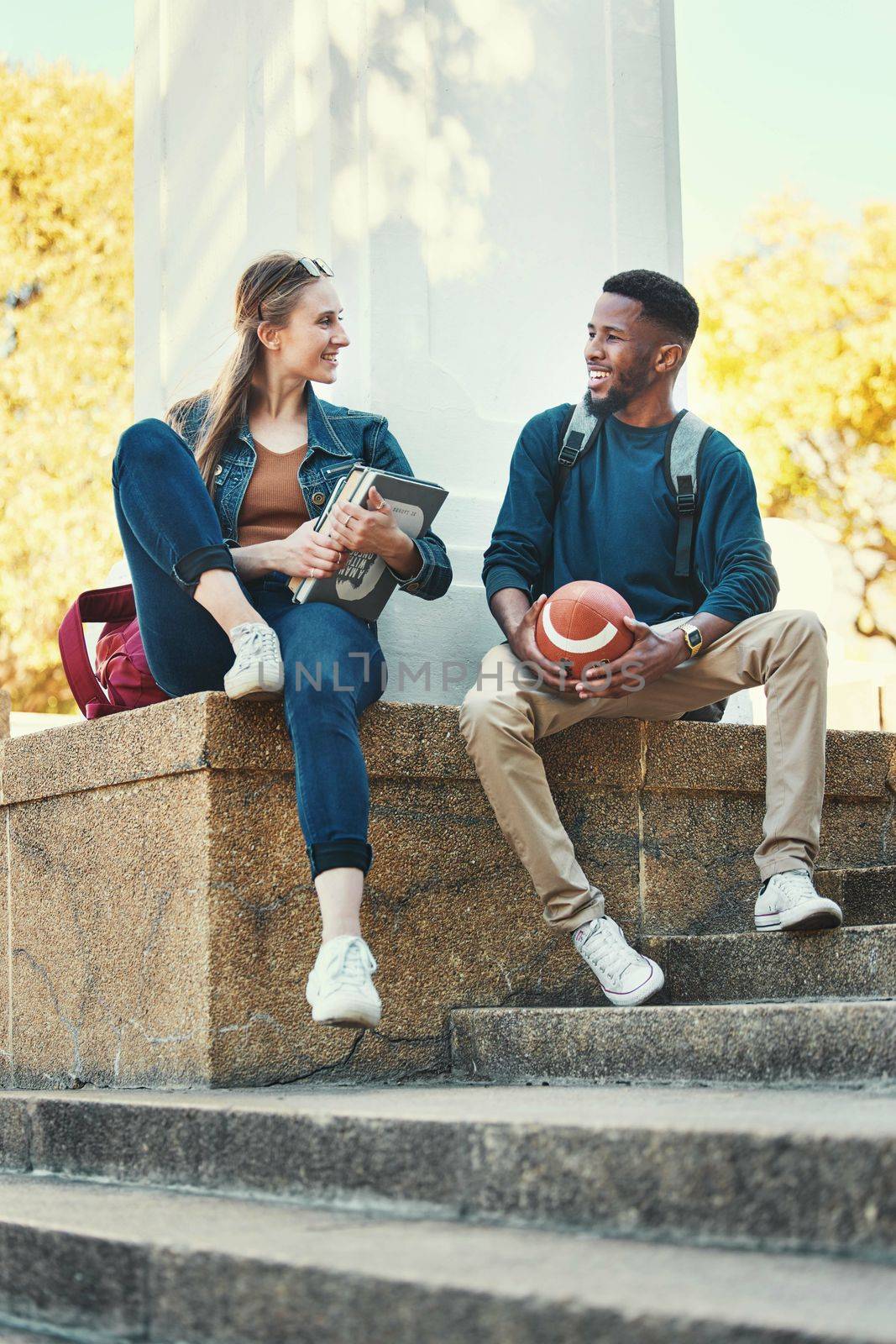 Students, relax and friends in college park for study, education and happy learning. University, woman with books and african sports man or university student together summer outdoor for happiness by YuriArcurs