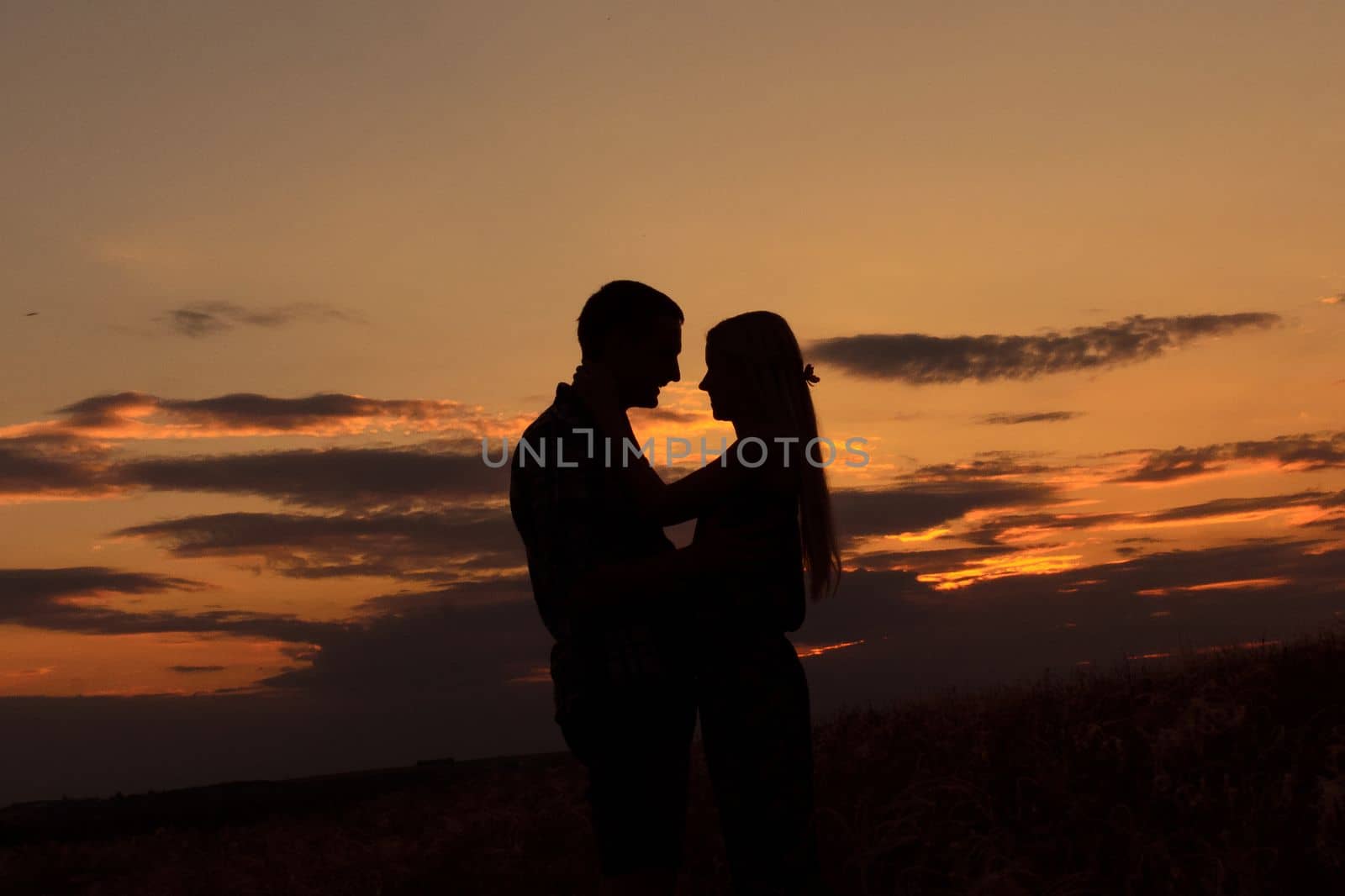 couple in love blonde girl in silhouette against an orange sunset