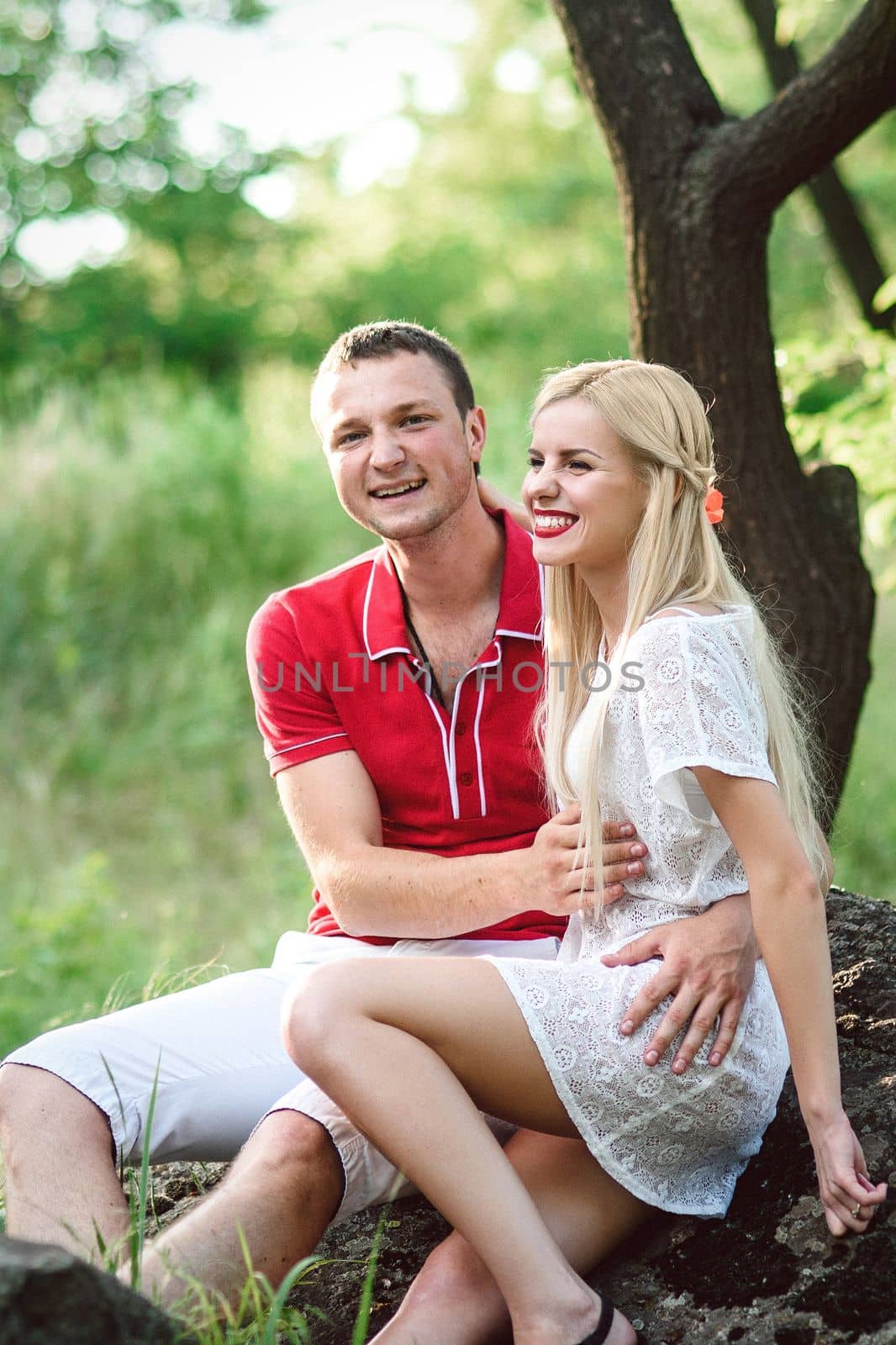 couple in love a blonde girl and a guy in a red t-shirt at a picnic in a park with green grass