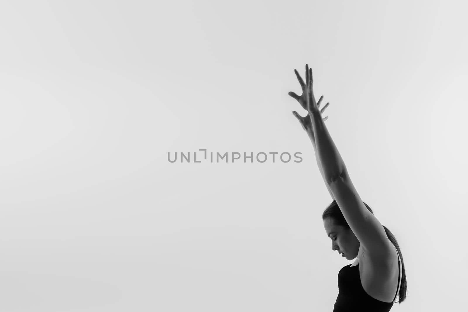 Portrait of beautiful young woman wearing black sportswear working out in studio. Full length. by Zelenin