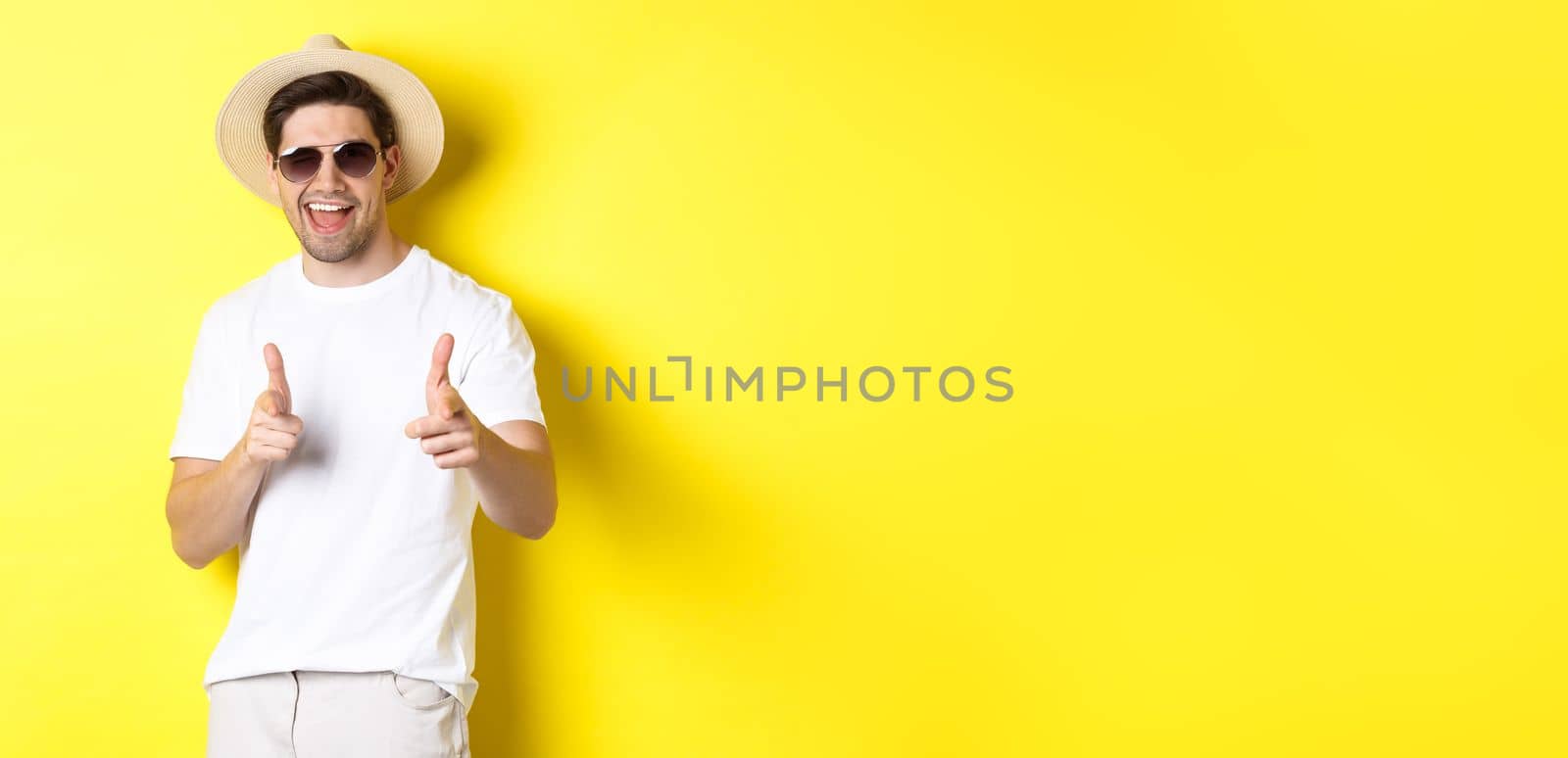 Confident and cheeky guy on vacation flirting with you, pointing finger at camera and winking, wearing summer hat with sunglasses, yellow background by Benzoix